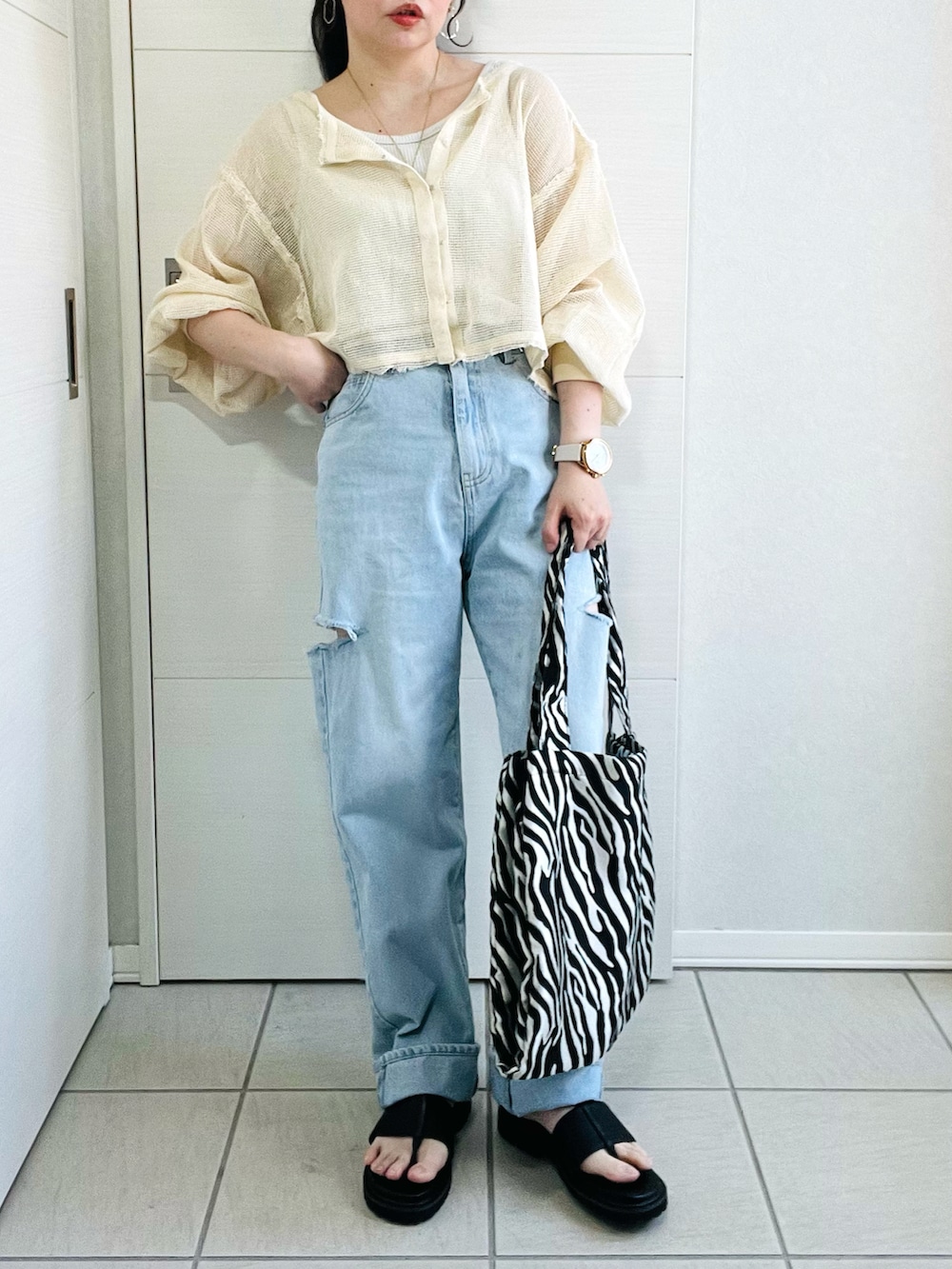 ホワイト系のカーディガン/ボレロ、ブルー系のデニムパンツ、ブラック系のサンダルを着用したレディースの春コーディネートの4枚目の写真