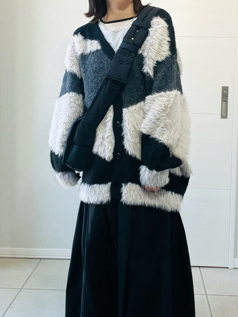 ブラック系のカーディガン/ボレロ、ブラック系のスニーカー、ブラック系のスカートを着用したレディースの秋コーディネートの2枚目の写真