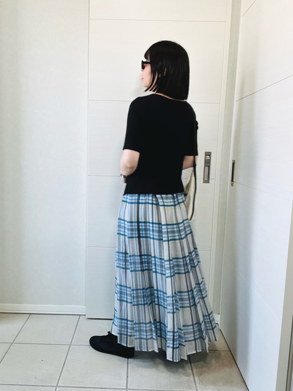 ブラック系のTシャツ/カットソー、ホワイト系のスカート、ブラック系のスニーカーを着用したレディースの秋コーディネートの4枚目の写真