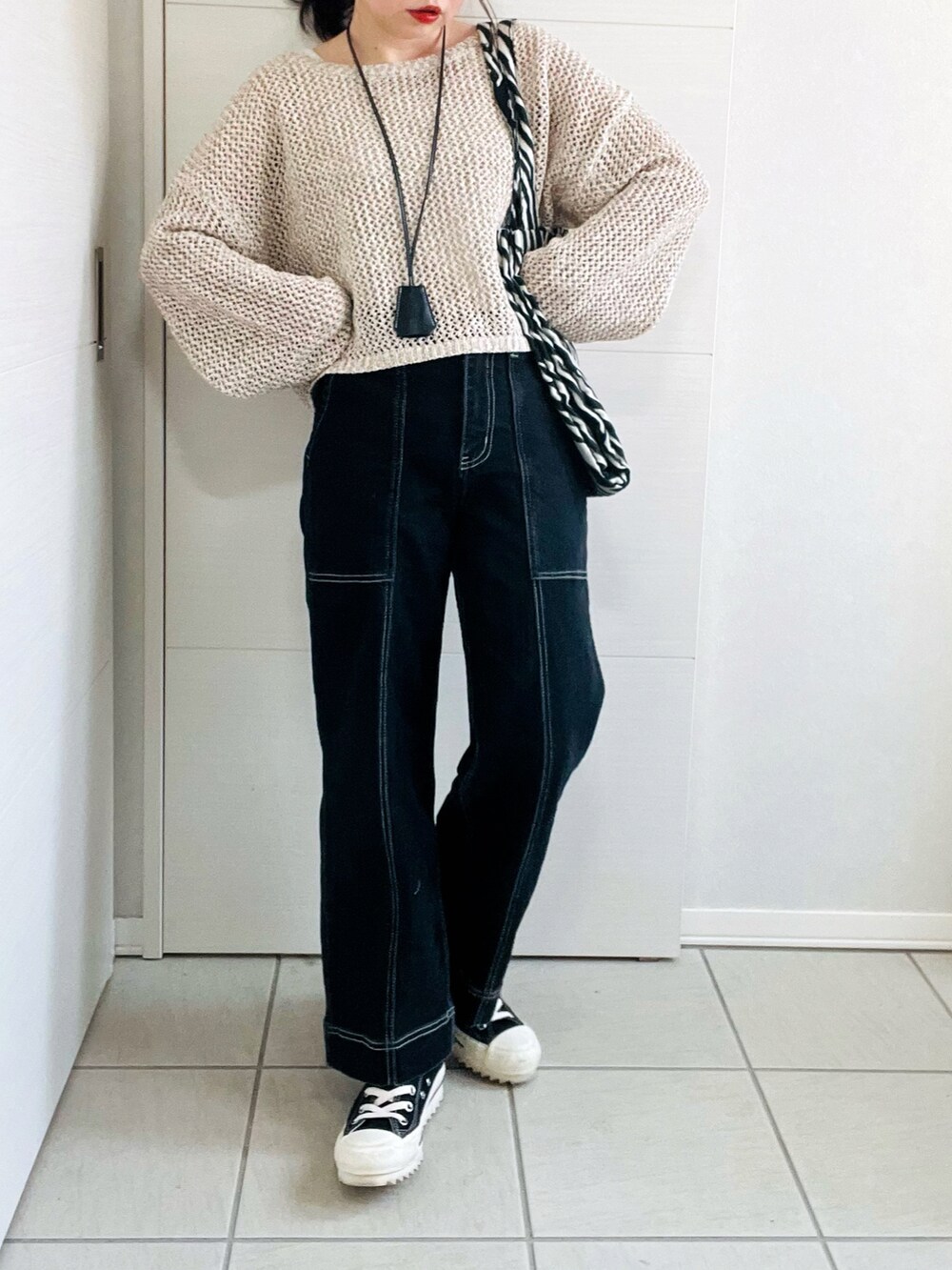 ベージュ系のニット/セーター、ブラック系のデニムパンツ、ブラック系のスニーカーを着用したレディースの春コーディネートの3枚目の写真