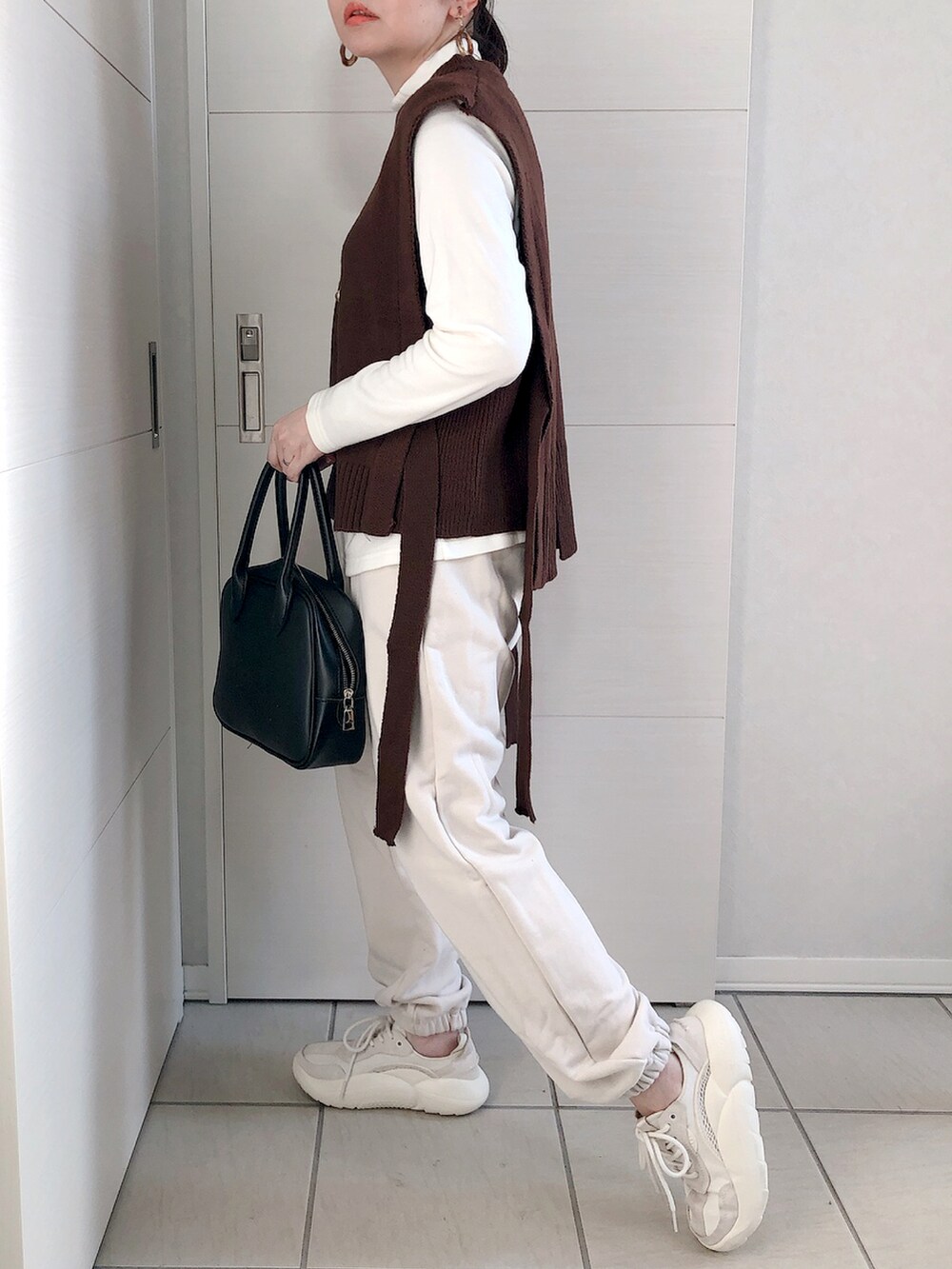 ブラウン系のベスト、ホワイト系のTシャツ/カットソー、ホワイト系のスウェットパンツを着用したレディースの冬コーディネートの3枚目の写真