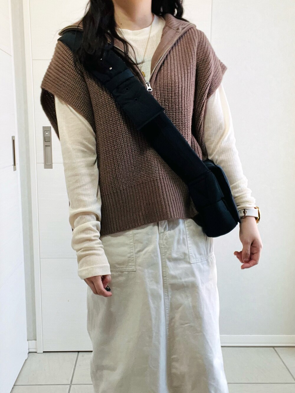 ブラウン系のベスト、ホワイト系のTシャツ/カットソー、ホワイト系のスカートを着用したレディースの秋コーディネートの3枚目の写真