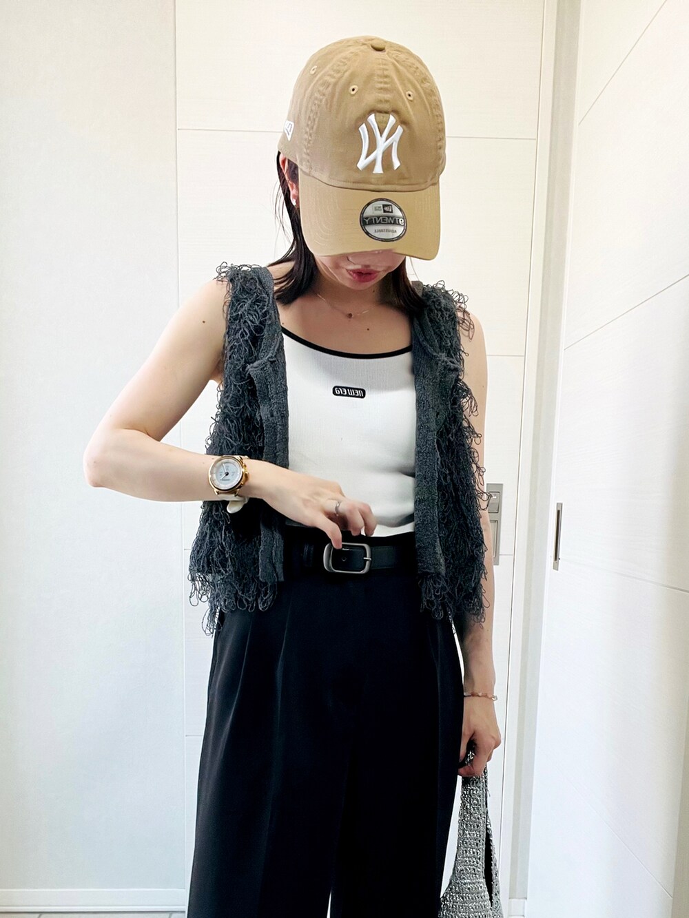 ホワイト系のキャミソール、グレー系のベスト、ブラック系のスラックスを着用したレディースの夏コーディネートの2枚目の写真