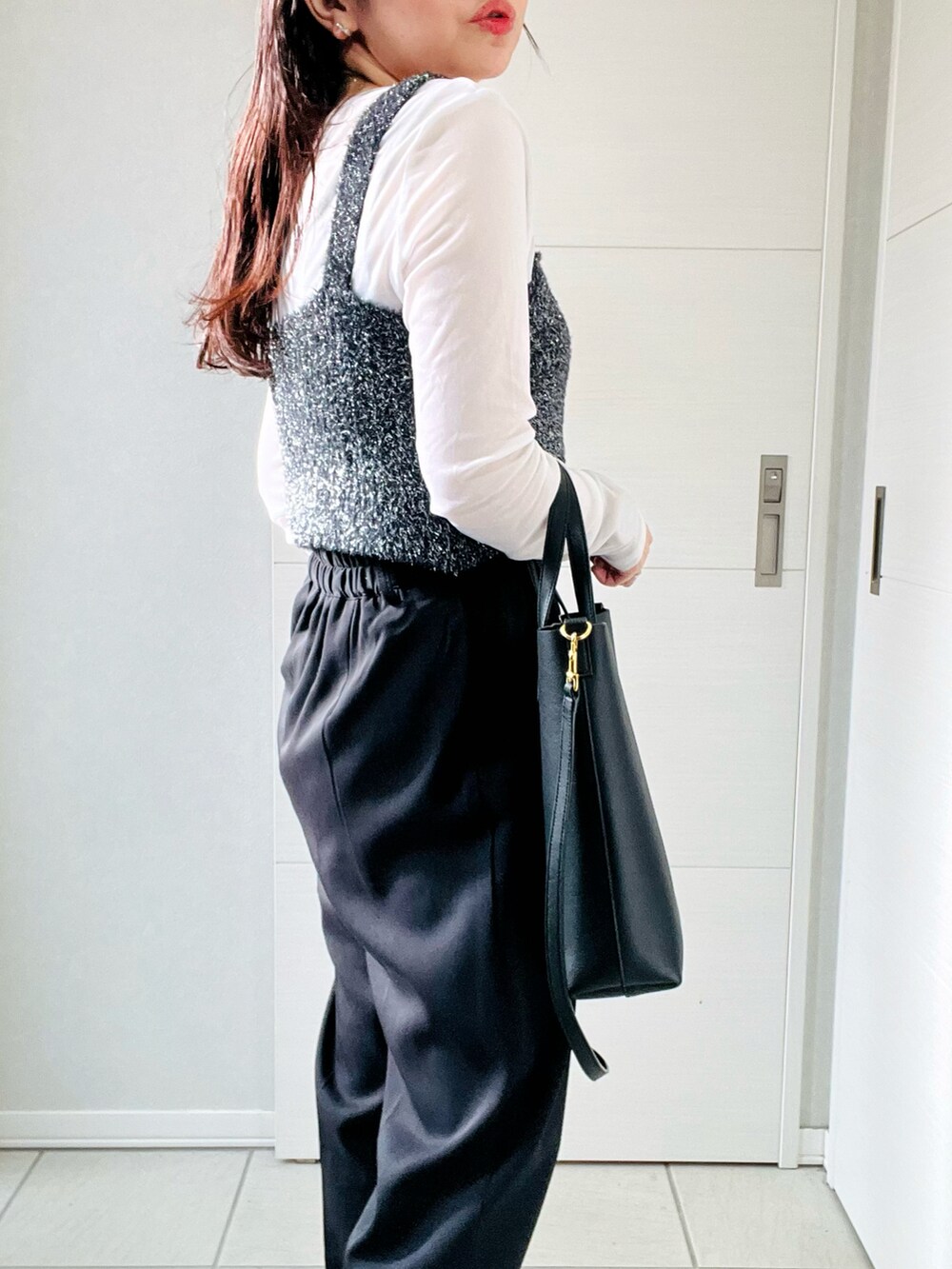 ブラック系のベスト、ホワイト系のTシャツ/カットソー、ブラック系のスラックスを着用したレディースの秋コーディネートの3枚目の写真