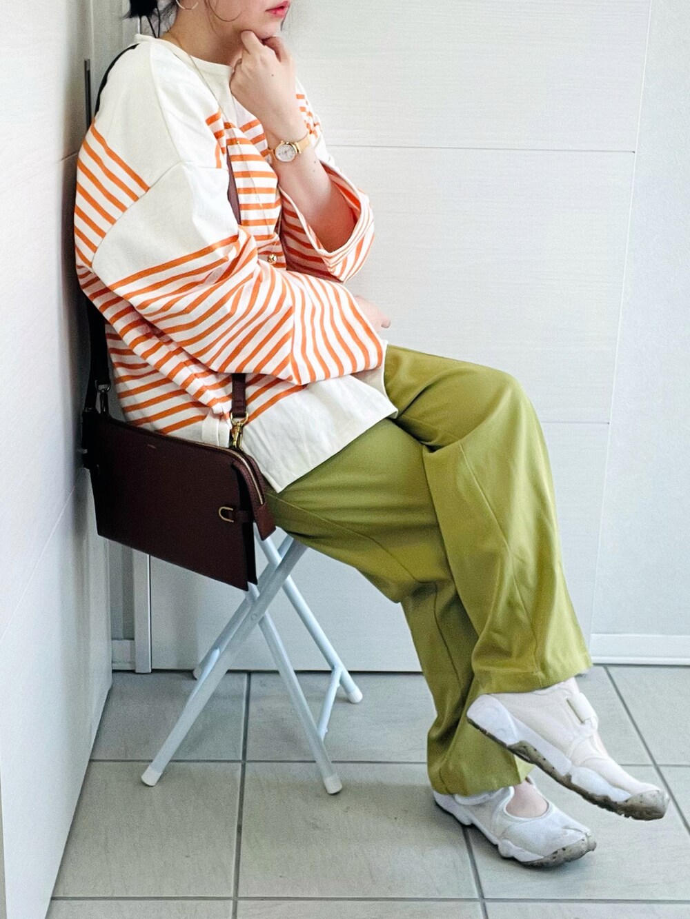 オレンジ系のTシャツ/カットソー、グリーン系のスラックス、ホワイト系のスニーカーを着用したレディースの春コーディネートの4枚目の写真