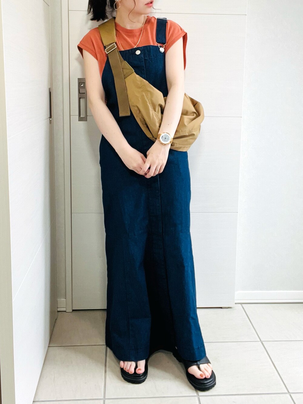 グリーン系のショルダーバッグ、オレンジ系のTシャツ/カットソー、ブルー系のジャンパースカートを着用したレディースの夏コーディネートの5枚目の写真