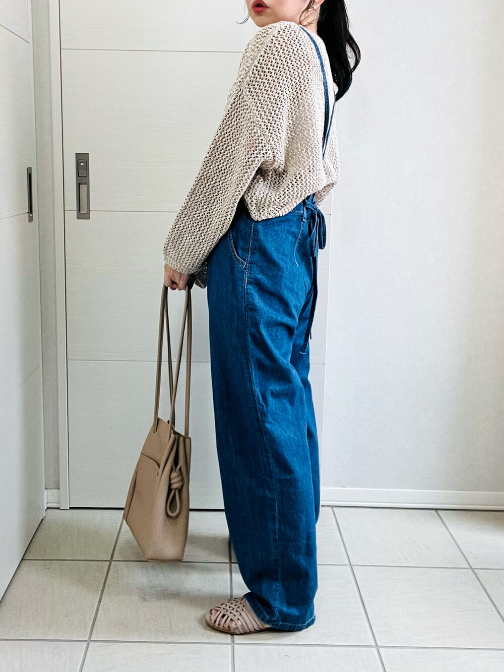 ブルー系のサロペット/オーバーオール、ベージュ系のニット/セーター、グレー系のサンダルを着用したレディースの春コーディネートの4枚目の写真