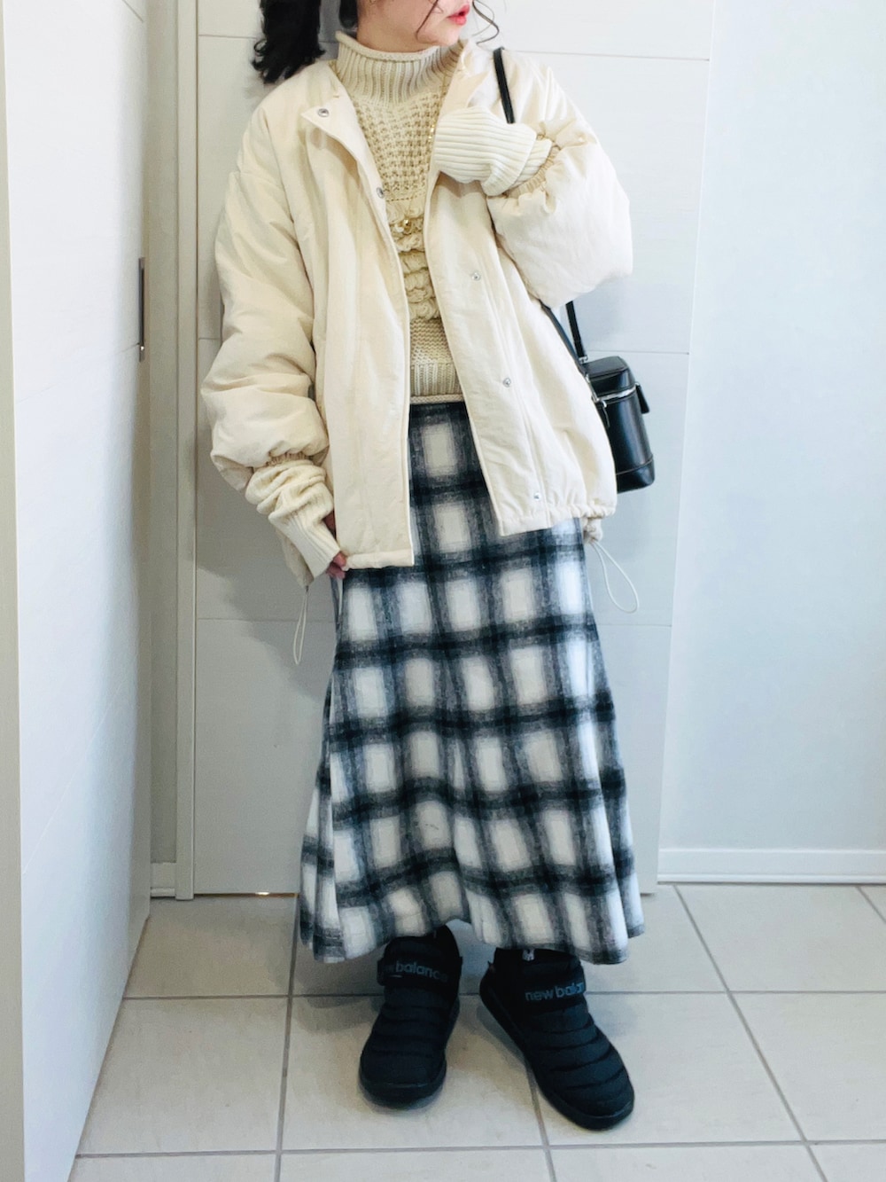 ホワイト系のブルゾン、ホワイト系のニット/セーター、ホワイト系のスカートを着用したレディースの冬コーディネートの3枚目の写真