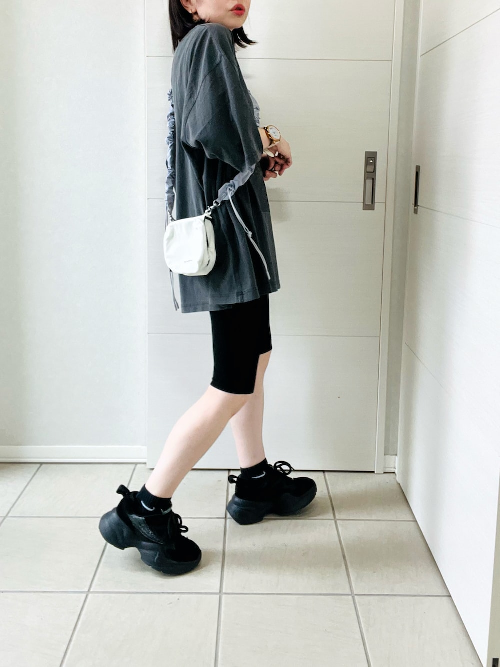 グレー系のTシャツ/カットソー、ブラック系のスニーカー、ホワイト系のショルダーバッグを着用したレディースの夏コーディネートの5枚目の写真