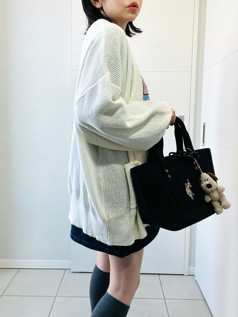 ホワイト系のカーディガン/ボレロ、グレー系のTシャツ/カットソー、ブルー系のデニムスカートを着用したレディースの春コーディネートの3枚目の写真