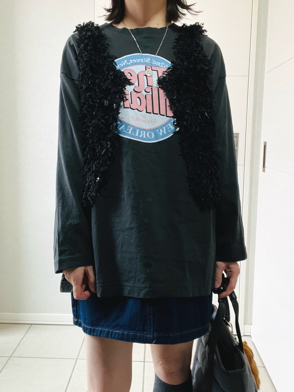 ブラック系のベスト、グレー系のTシャツ/カットソー、ブルー系のデニムスカートを着用したレディースの春コーディネートの2枚目の写真