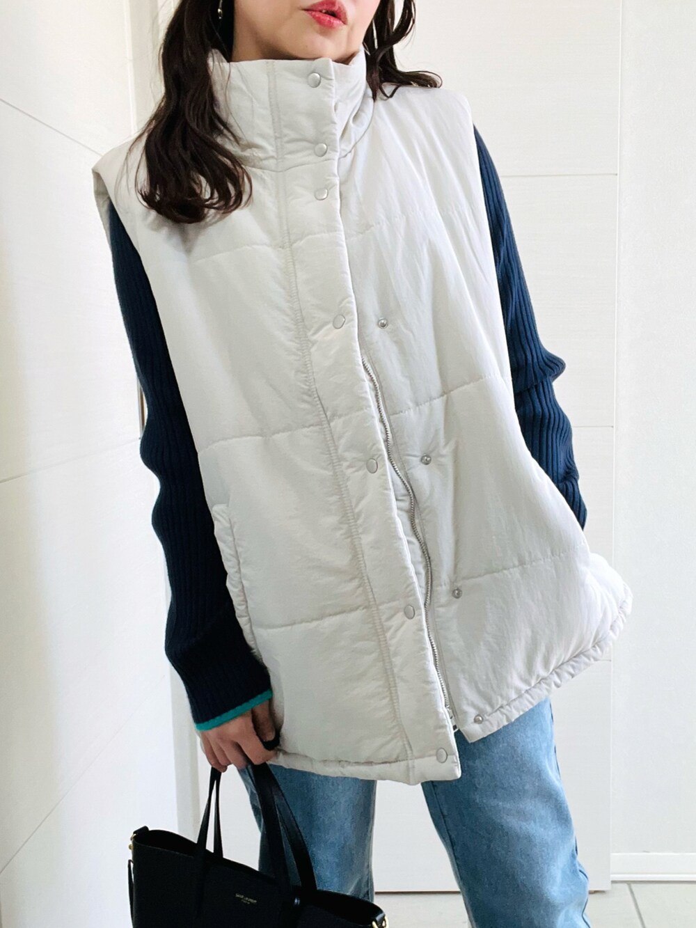 ホワイト系のベスト、ブルー系のデニムパンツ、ブルー系のニット/セーターを着用したレディースの秋コーディネートの3枚目の写真