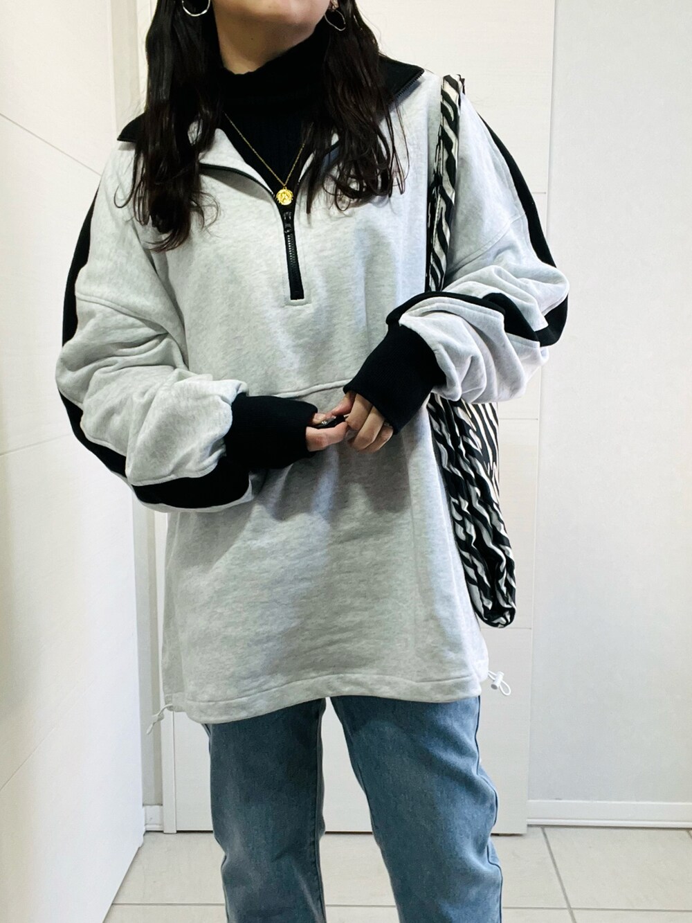 グレー系のスウェット、ブルー系のデニムパンツ、ブラウン系のブーツを着用したレディースの冬コーディネートの2枚目の写真