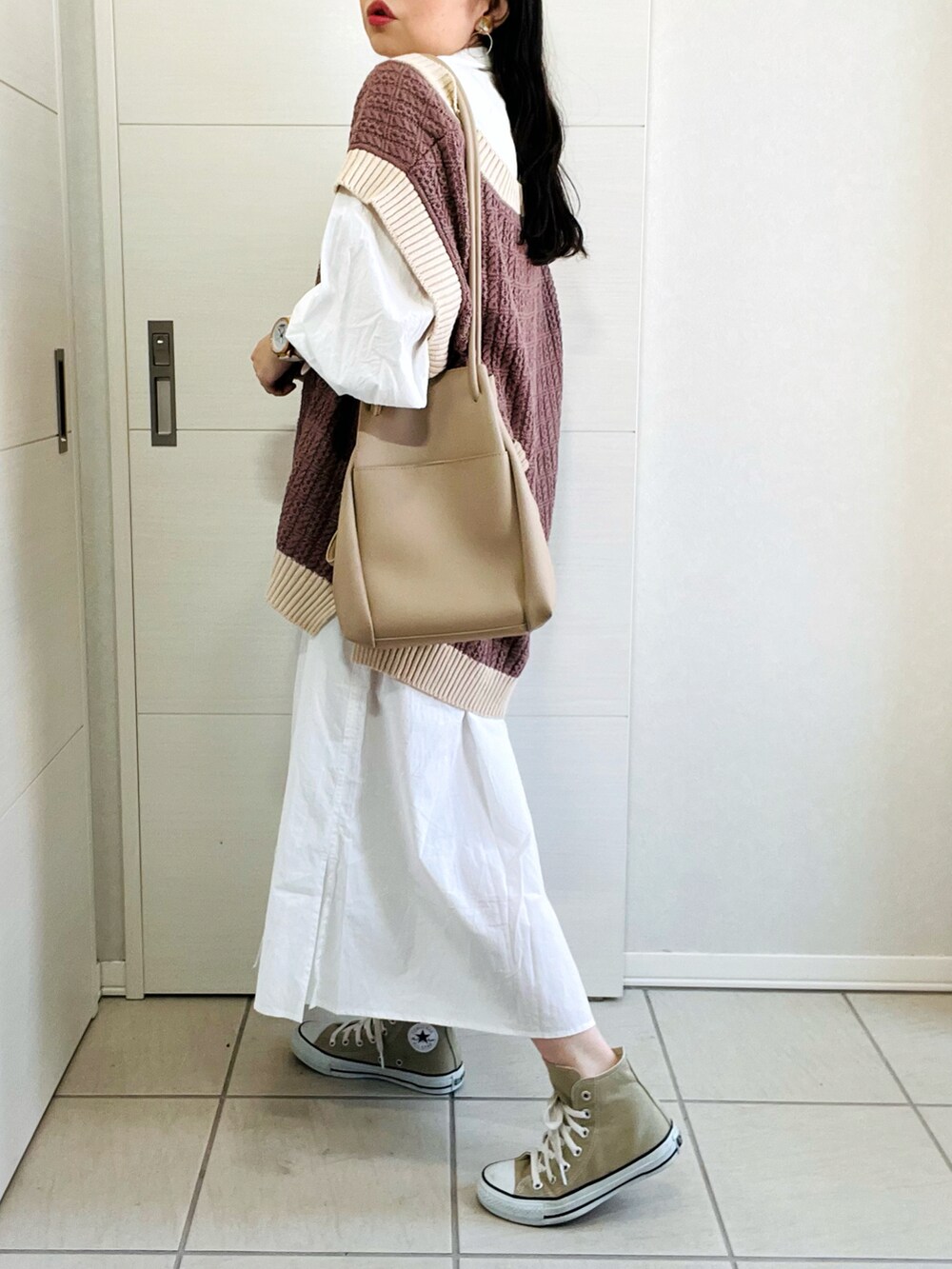 ブラウン系のベスト、ホワイト系のワンピース、ベージュ系のスニーカーを着用したレディースの秋コーディネートの5枚目の写真