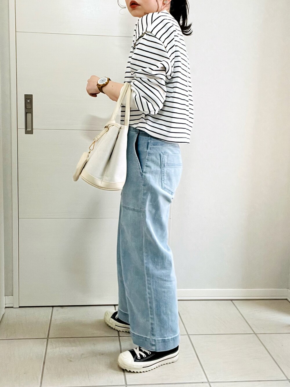 ブラック系のワンピース、ブルー系のデニムパンツ、ブラック系のスニーカーを着用したレディースの春コーディネートの4枚目の写真