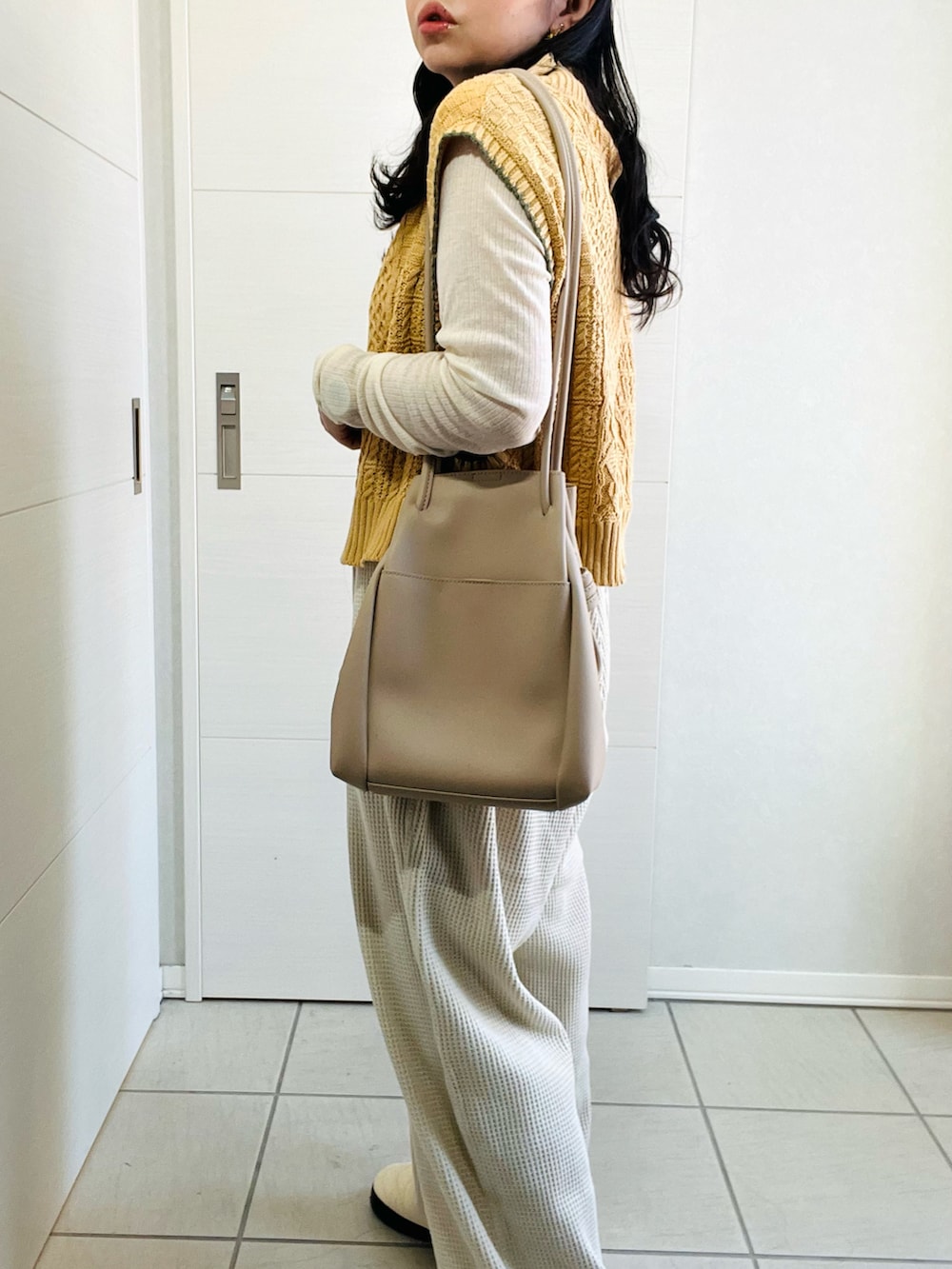 イエロー系のベスト、ホワイト系のTシャツ/カットソー、ベージュ系のその他パンツを着用したレディースの秋コーディネートの3枚目の写真