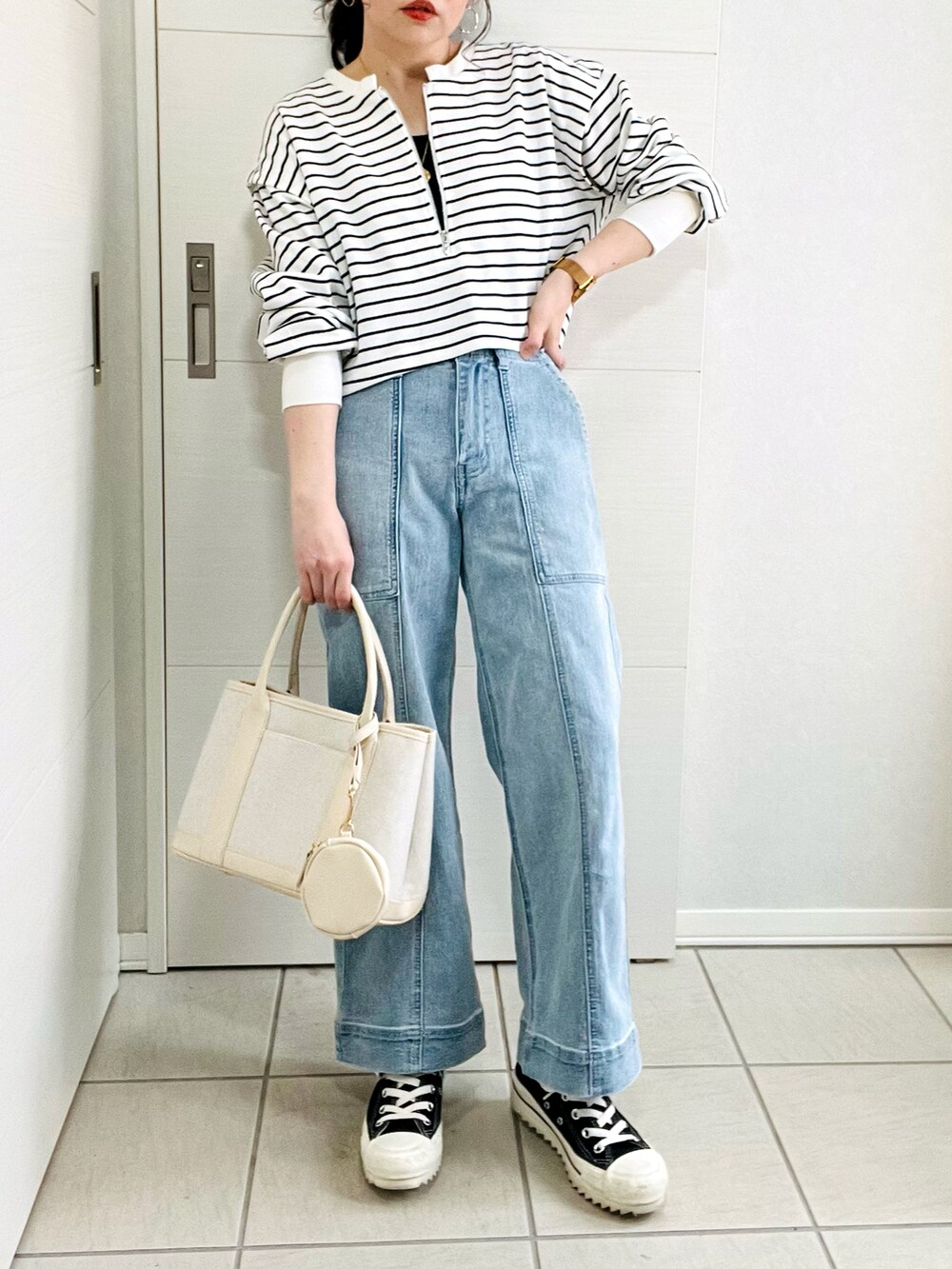 ブラック系のワンピース、ブルー系のデニムパンツ、ブラック系のスニーカーを着用したレディースの春コーディネートの3枚目の写真