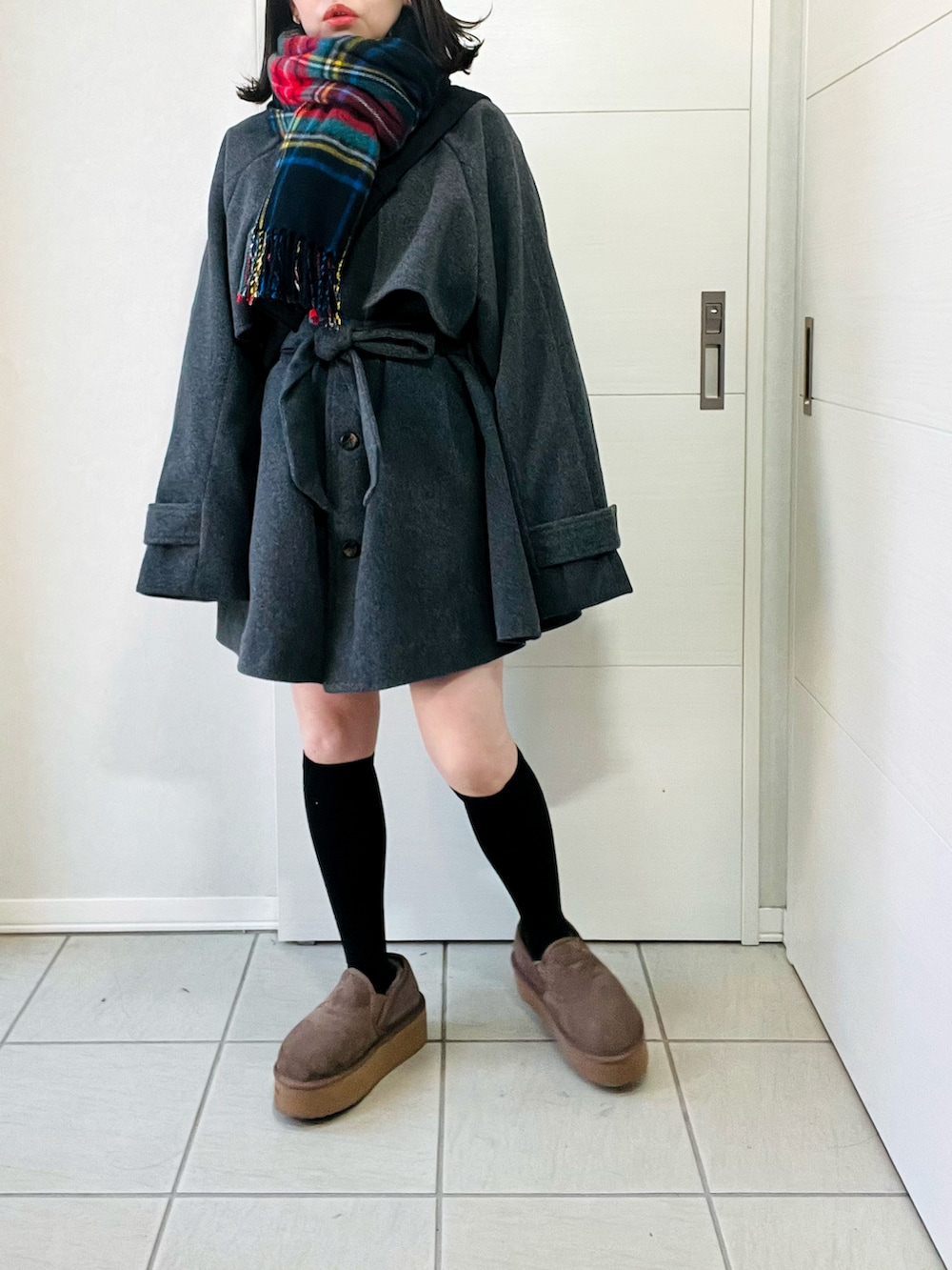 グレー系のトレンチコート、ベージュ系のスリッポン、ブラック系のショルダーバッグを着用したレディースの秋コーディネートの4枚目の写真