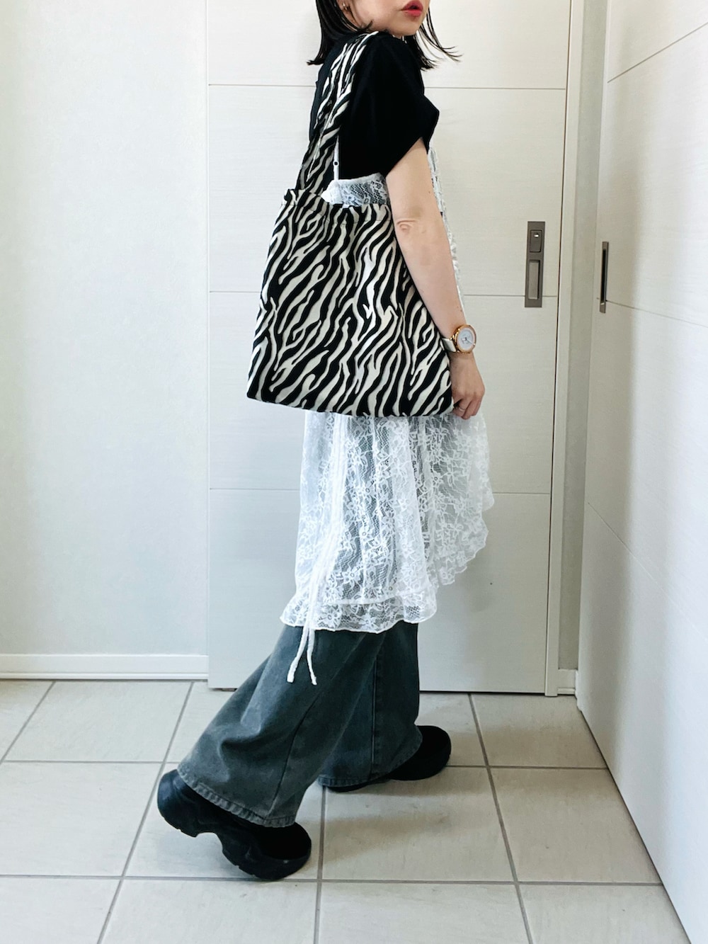 ホワイト系のチュニック、ブラック系のTシャツ/カットソー、ブルー系のデニムパンツを着用したレディースの春コーディネートの4枚目の写真