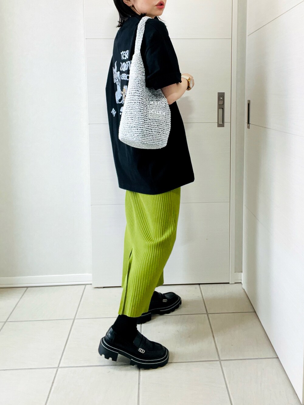 ブラック系のTシャツ/カットソー、グリーン系のスカート、ブラック系のローファーを着用したレディースの春コーディネートの5枚目の写真