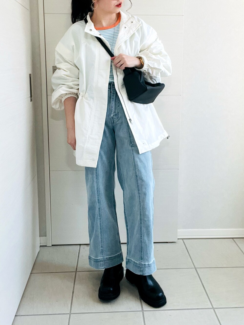 ホワイト系のブルゾン、ブルー系のTシャツ/カットソー、ブルー系のデニムパンツを着用したレディースの冬コーディネートの2枚目の写真