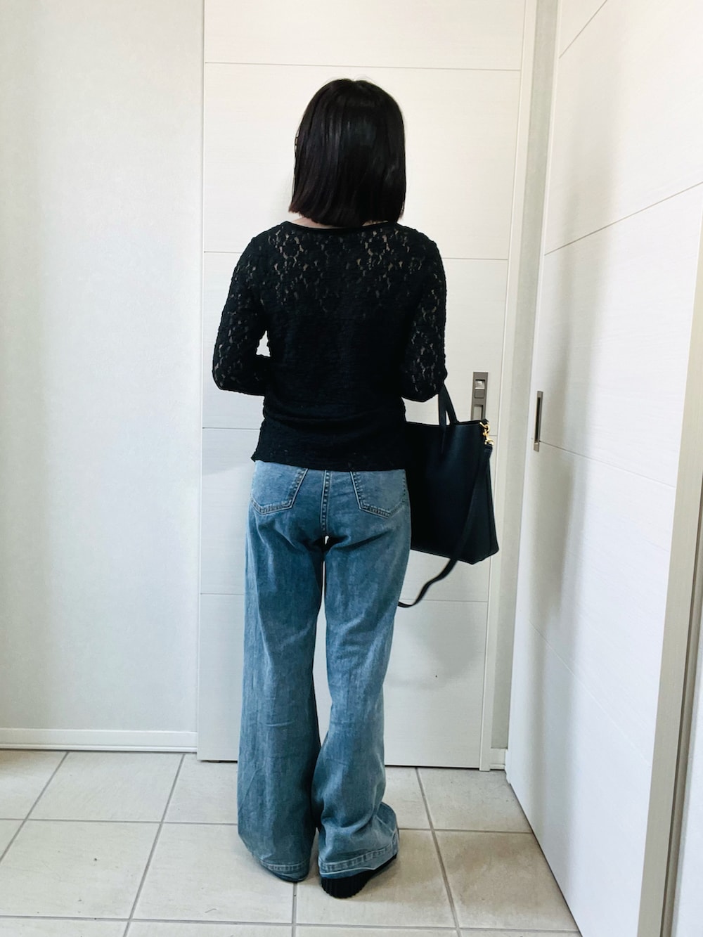 ブラック系のシャツ/ブラウス、ブラック系のブーツ、ブルー系のデニムパンツを着用したレディースの秋コーディネートの4枚目の写真