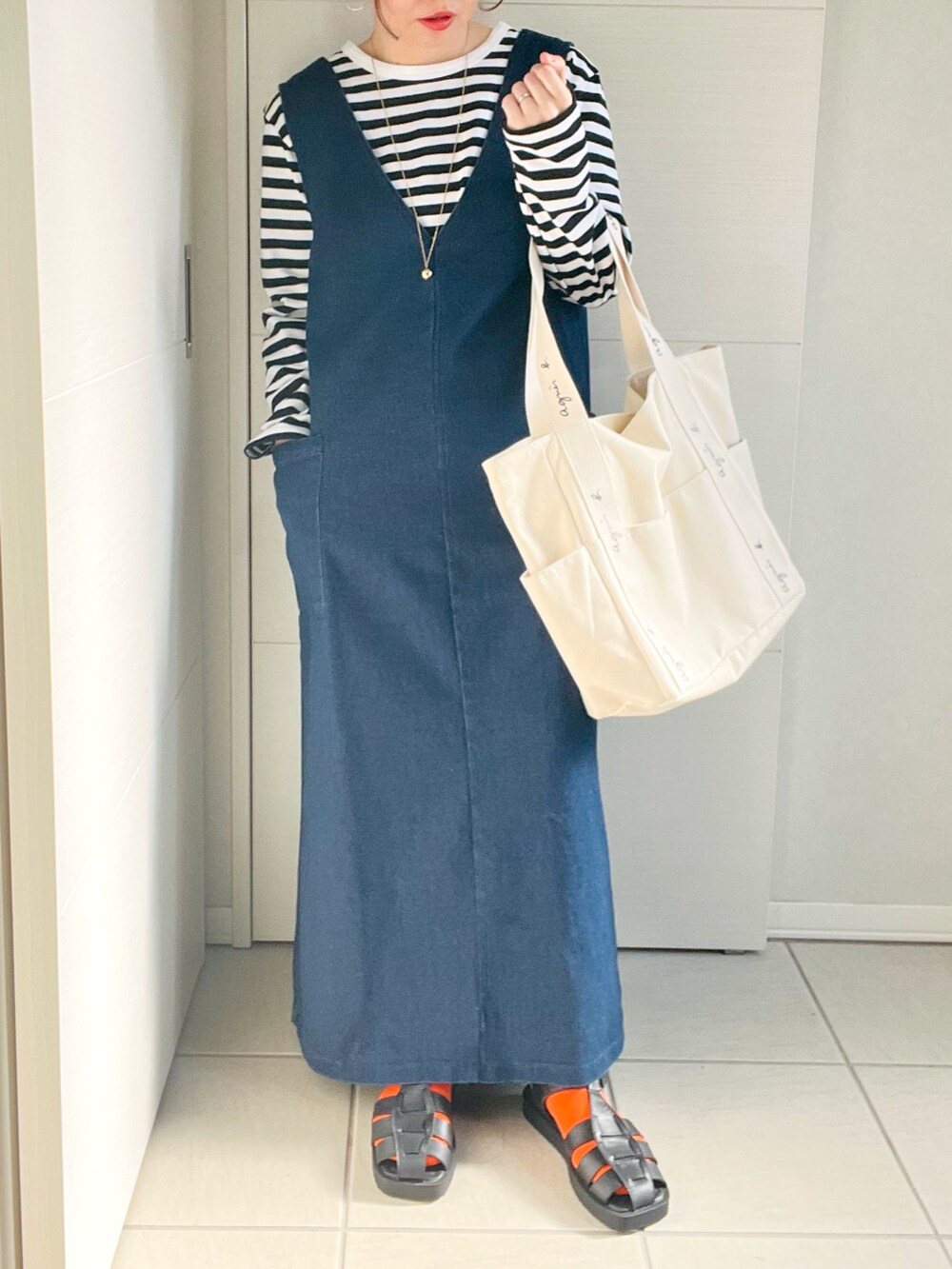 ブラック系のTシャツ/カットソー、ブルー系のワンピース、ブラック系のサンダルを着用したレディースの春コーディネートの2枚目の写真