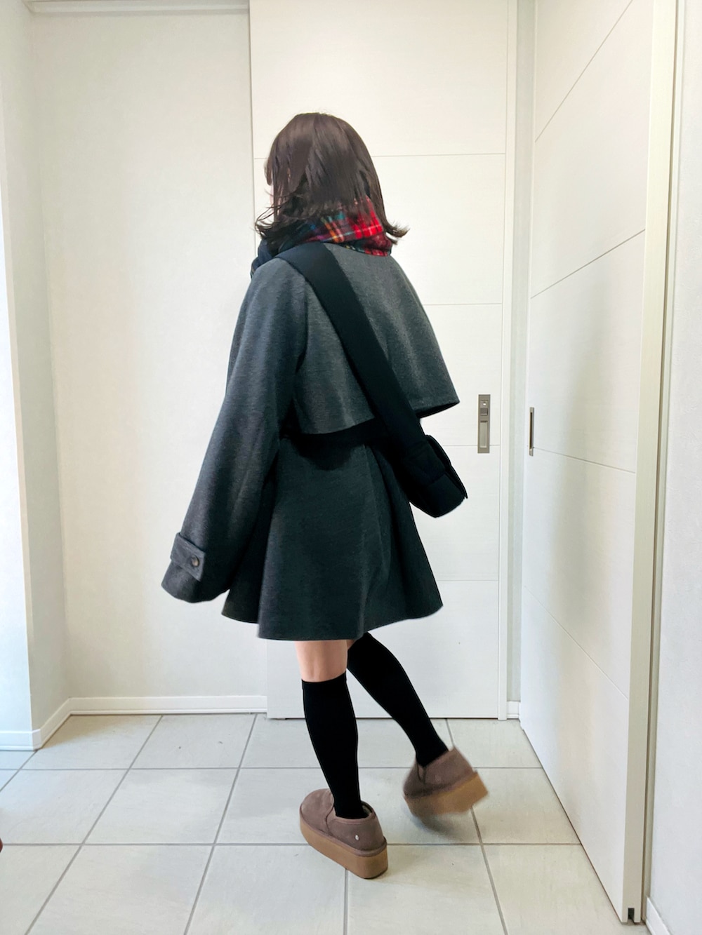 グレー系のトレンチコート、ベージュ系のスリッポン、ブラック系のショルダーバッグを着用したレディースの秋コーディネートの3枚目の写真