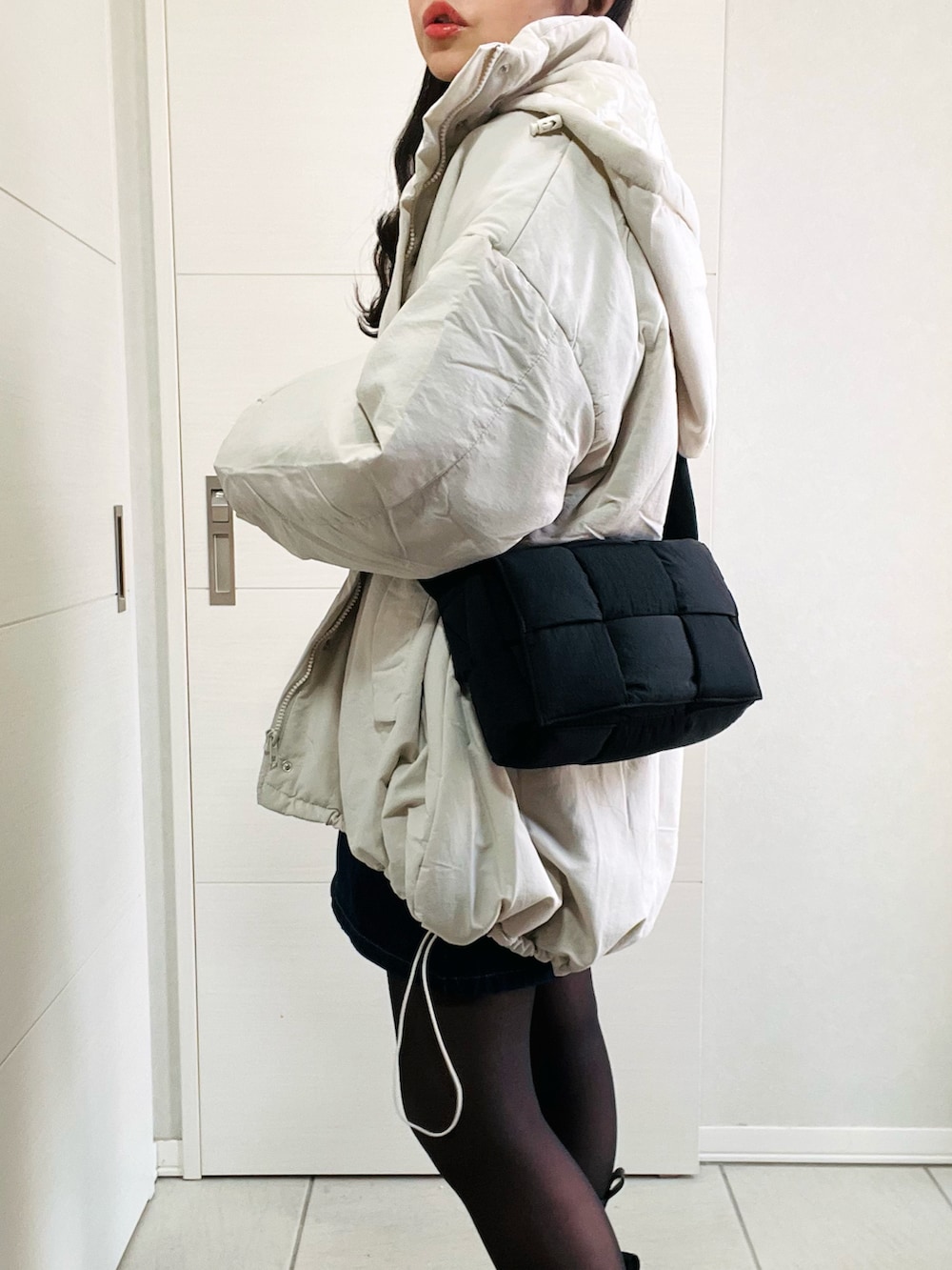 ホワイト系のダウンジャケット/コート、グレー系のニット/セーター、ブルー系のデニムスカートを着用したレディースの冬コーディネートの3枚目の写真