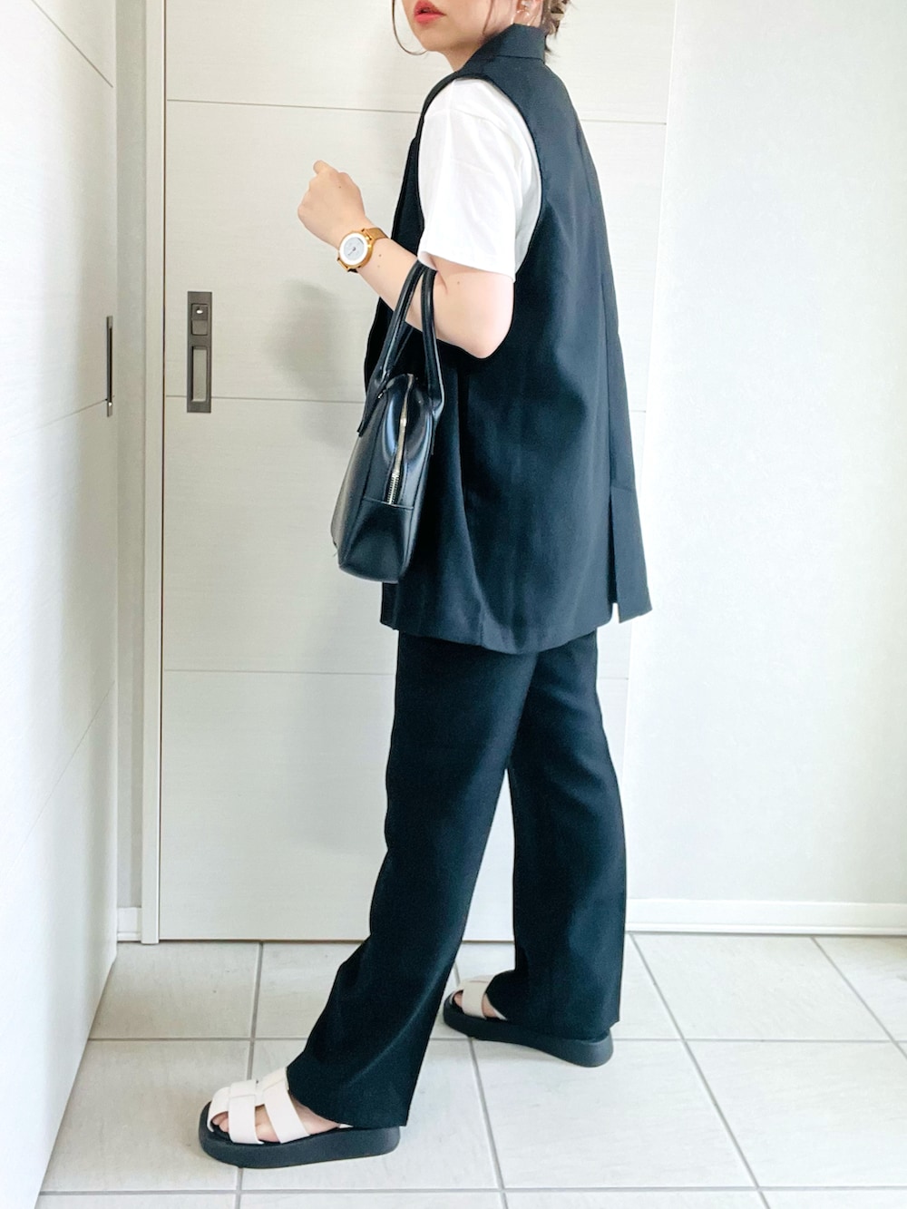 ブラック系のベスト、ホワイト系のTシャツ/カットソー、ブラック系のスラックスを着用したレディースの春コーディネートの4枚目の写真