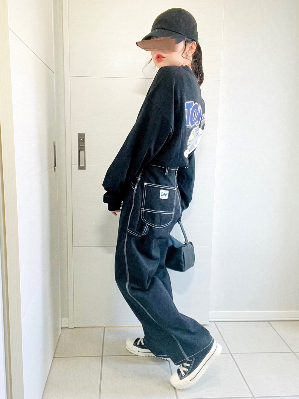 ブラック系のTシャツ/カットソー、ブラック系のデニムパンツ、ブラック系のスニーカーを着用したレディースの秋コーディネートの3枚目の写真