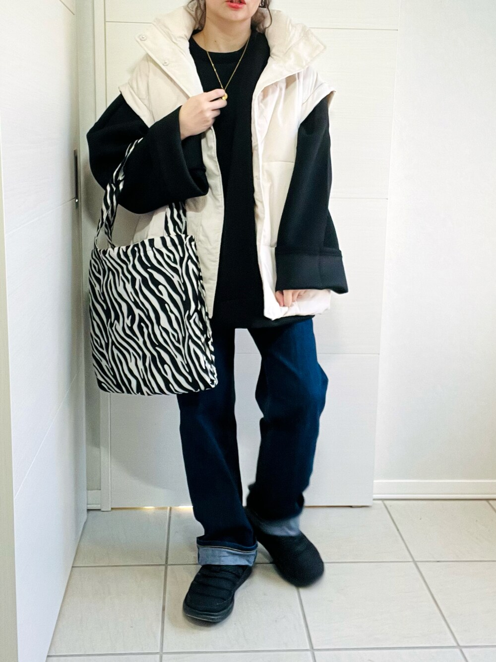 ブラック系のスウェット、ホワイト系のダウンジャケット/コート、ブルー系のデニムパンツを着用したレディースの冬コーディネートの5枚目の写真