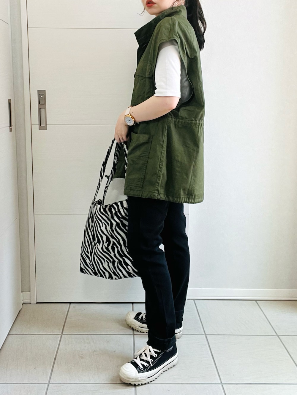 ホワイト系のTシャツ/カットソー、グリーン系のベスト、ブラック系のデニムパンツを着用したレディースの春コーディネートの3枚目の写真