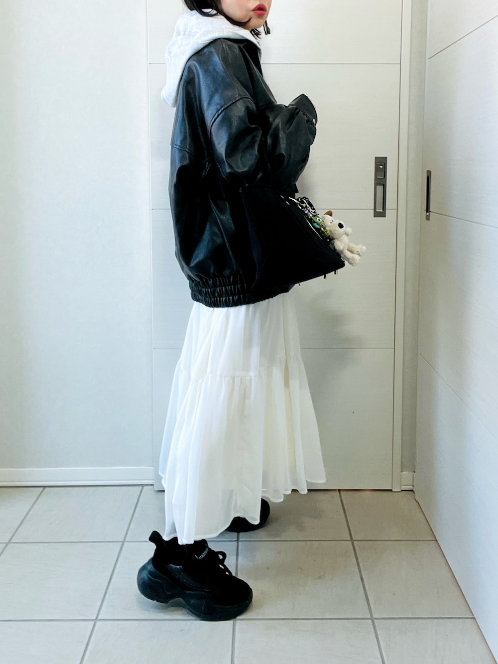 ブラック系のブルゾン、グレー系のパーカー、ホワイト系のスカートを着用したレディースの冬コーディネートの4枚目の写真