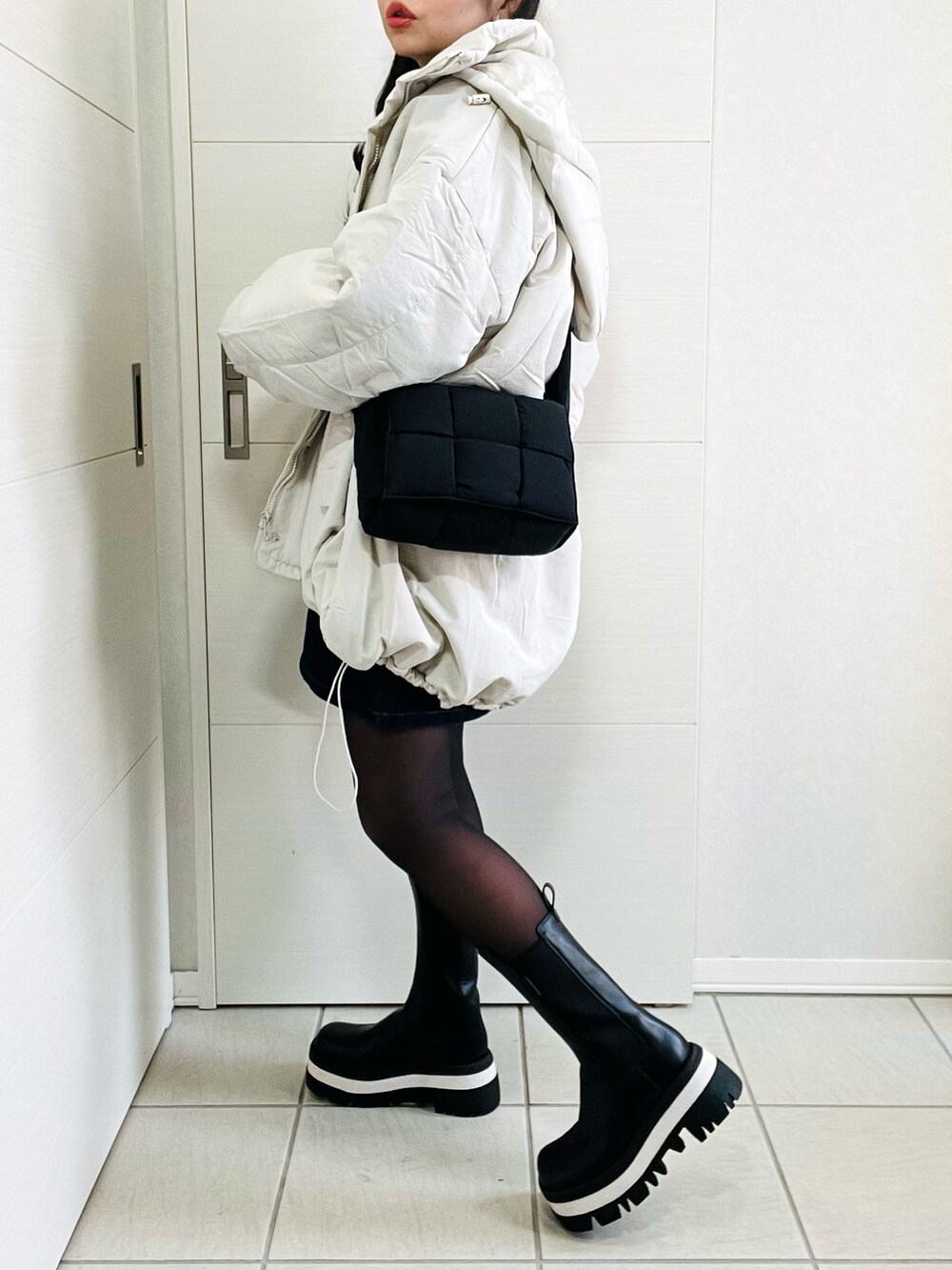 ホワイト系のダウンジャケット/コート、グレー系のニット/セーター、ブルー系のデニムスカートを着用したレディースの冬コーディネートの5枚目の写真