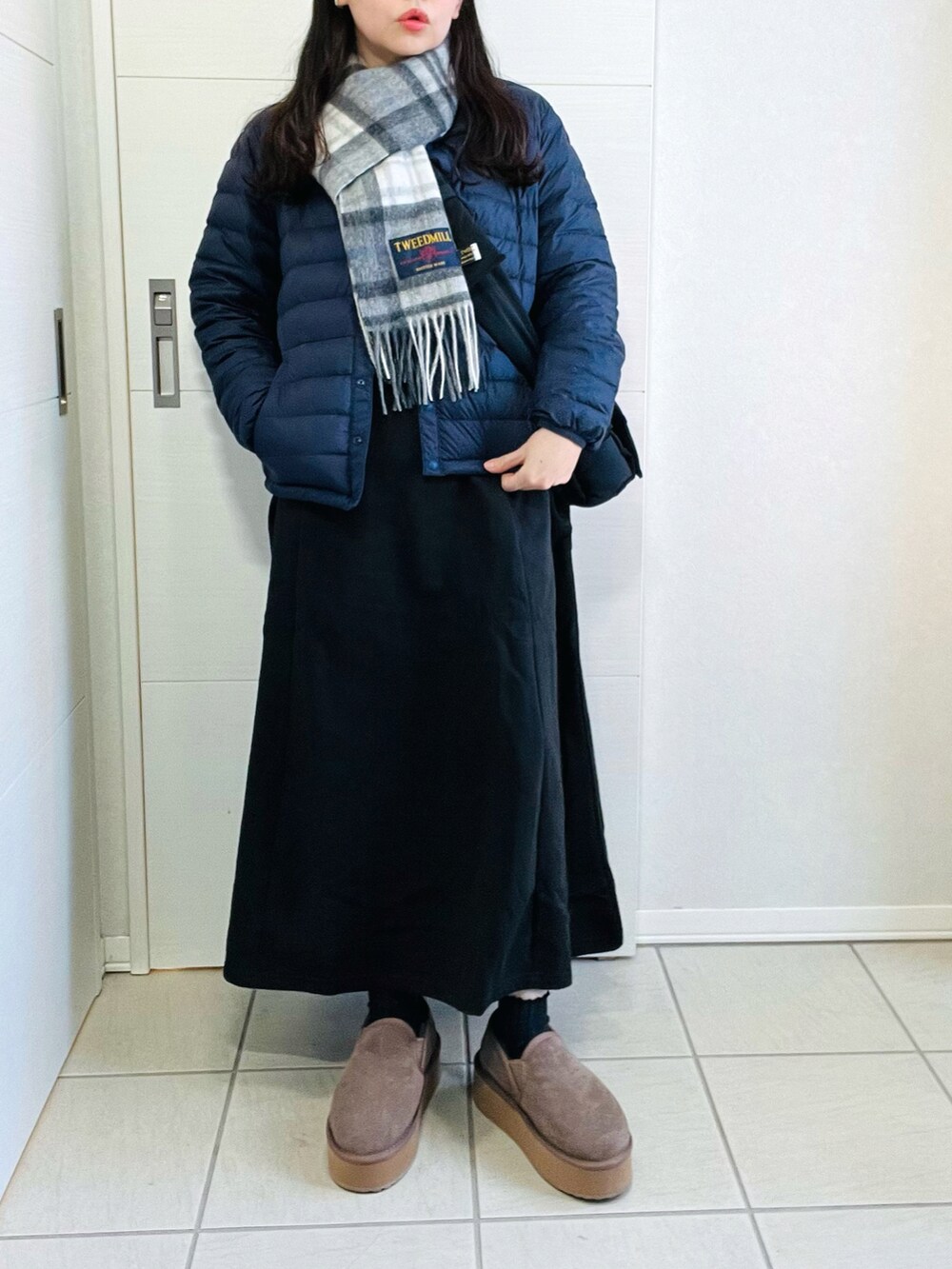 ブルー系のダウンジャケット/コート、ブラック系のワンピース、ベージュ系のスリッポンを着用したレディースの冬コーディネートの4枚目の写真