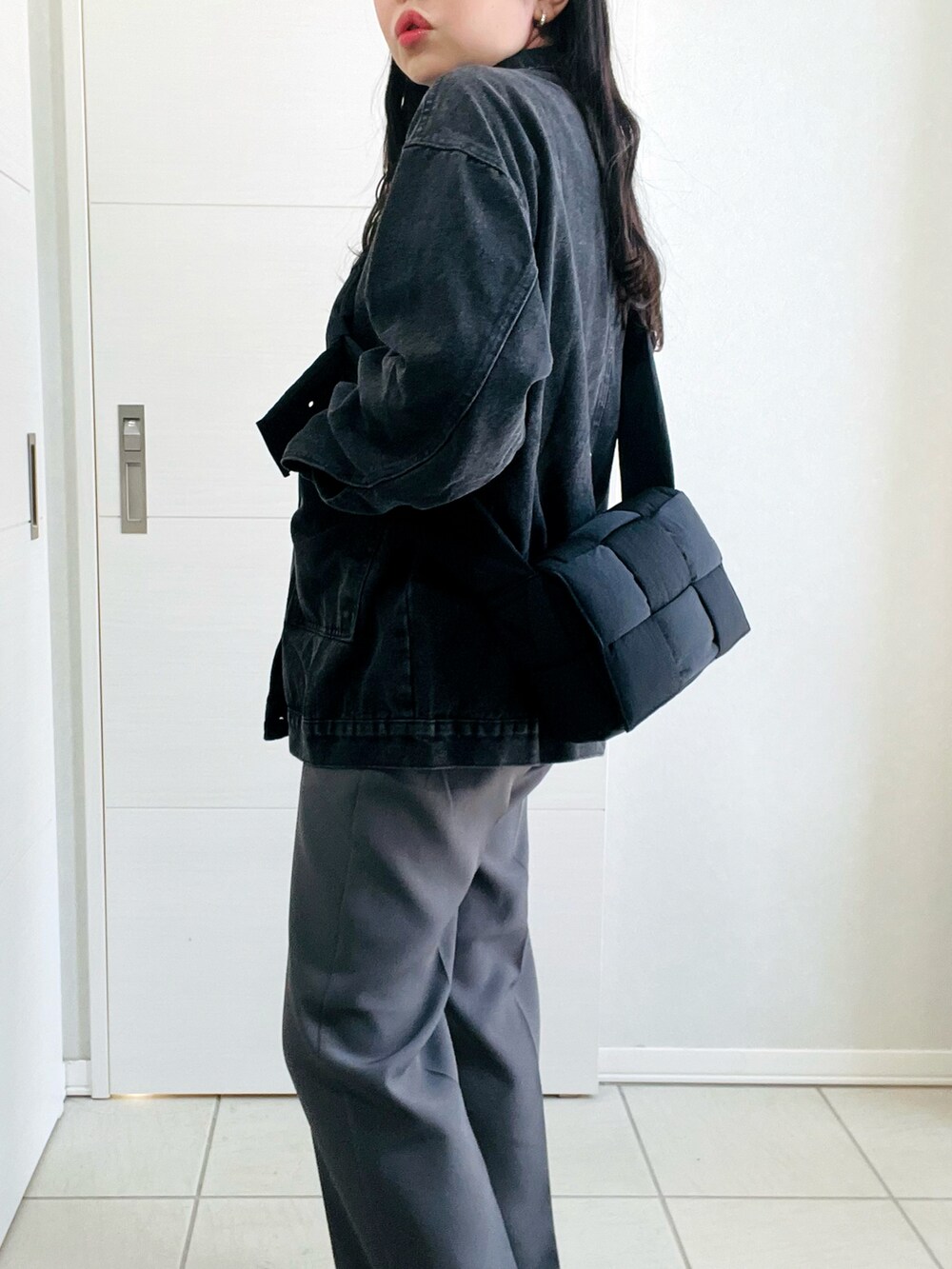 ブラック系のデニムジャケット、グレー系のスラックス、ブラック系のローファーを着用したレディースの春コーディネートの4枚目の写真