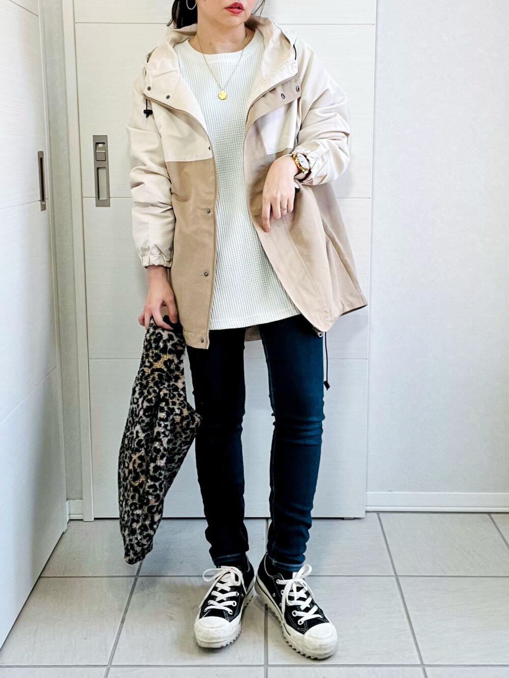 ベージュ系のマウンテンパーカー、ホワイト系のスウェット、ブルー系のデニムパンツを着用したレディースの秋コーディネートの4枚目の写真