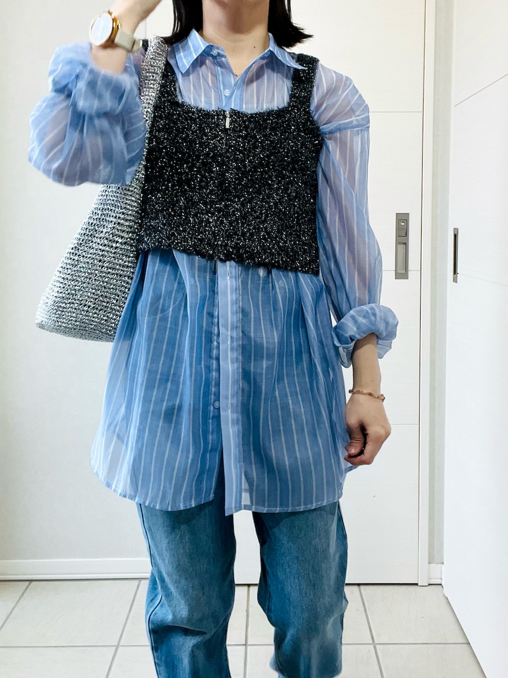 ブルー系のシャツ/ブラウス、ブラック系のベスト、ブルー系のデニムパンツを着用したレディースの春コーディネートの2枚目の写真