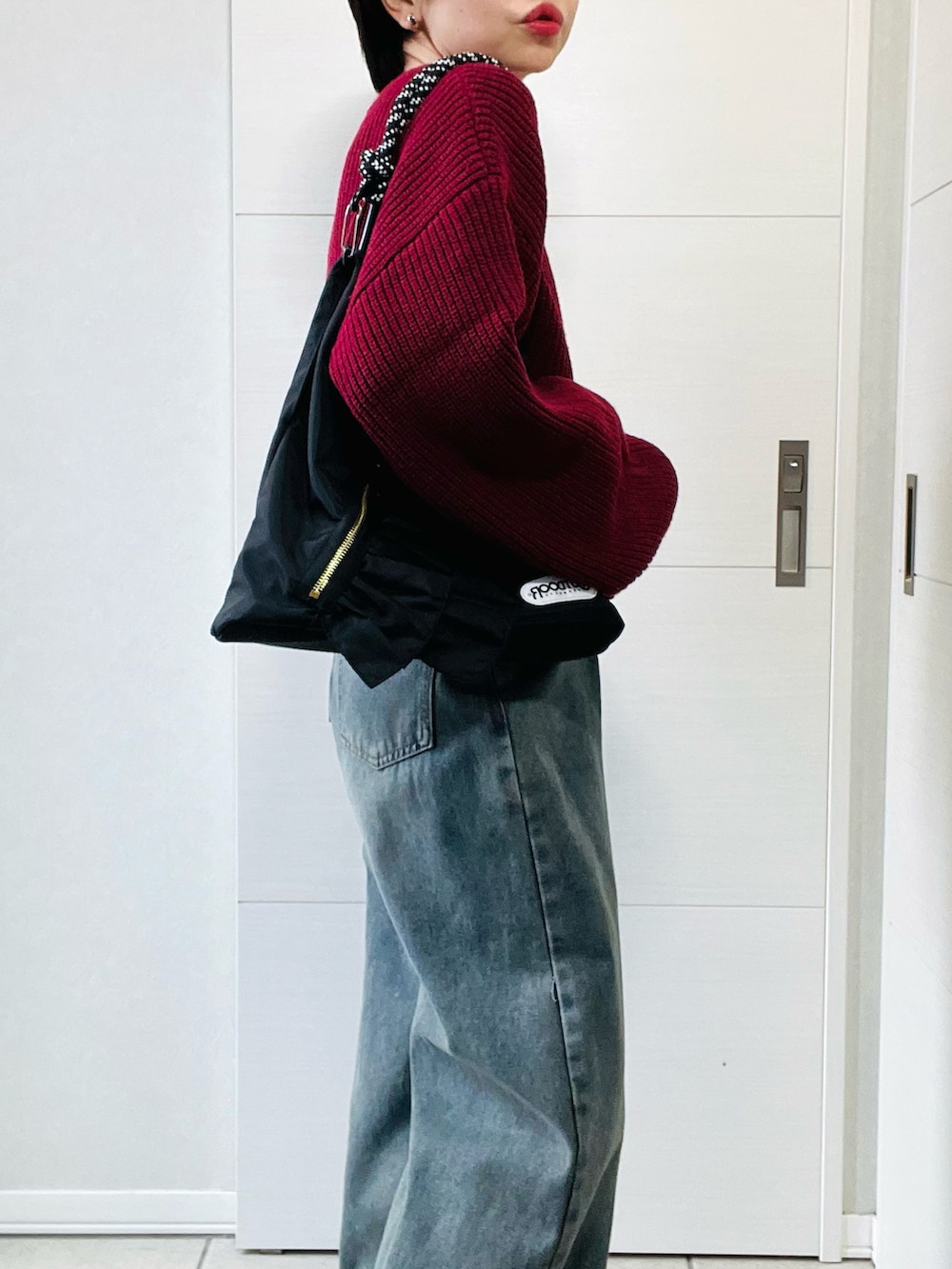 レッド系のカーディガン/ボレロ、ブラック系のブーツ、ブルー系のデニムパンツを着用したレディースの秋コーディネートの3枚目の写真