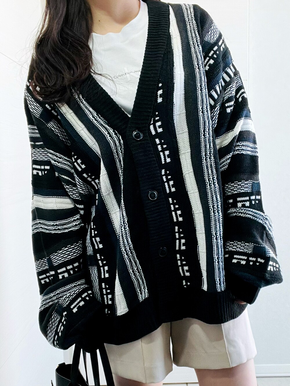 ブラック系のカーディガン/ボレロ、ホワイト系のスラックス、ブラック系のローファーを着用したレディースの春コーディネートの3枚目の写真