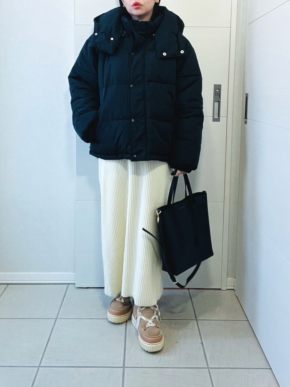 ブラック系のダウンジャケット/コート、グレー系のニット/セーター、ホワイト系のスカートを着用したレディースの冬コーディネートの2枚目の写真