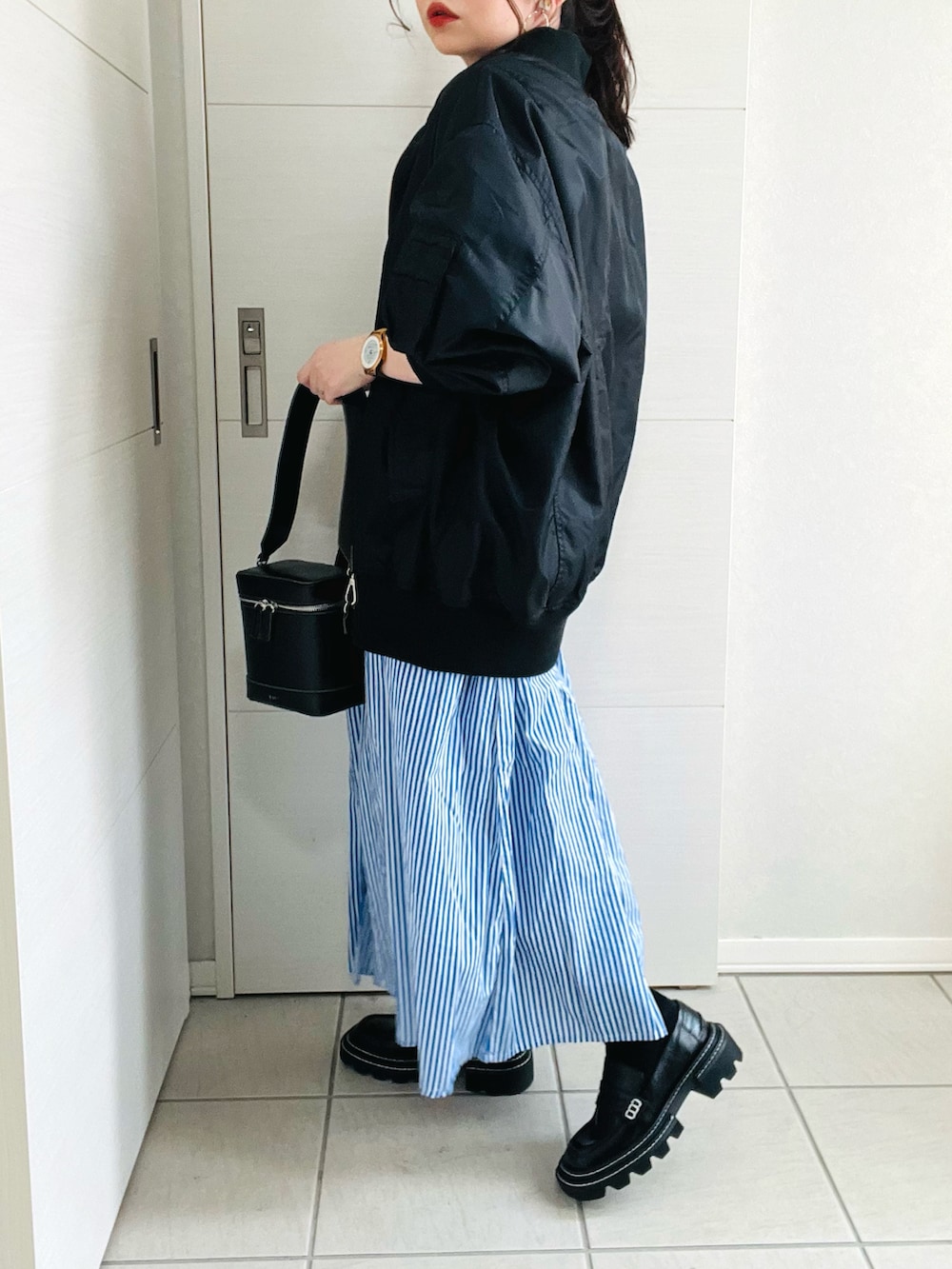 ブルー系のシャツワンピース、ブラック系のブルゾン、ブラック系のローファーを着用したレディースの春コーディネートの4枚目の写真