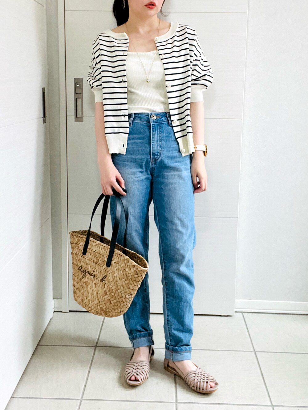 ホワイト系のタンクトップ、ホワイト系のカーディガン/ボレロ、ブルー系のデニムパンツを着用したレディースの夏コーディネートの2枚目の写真