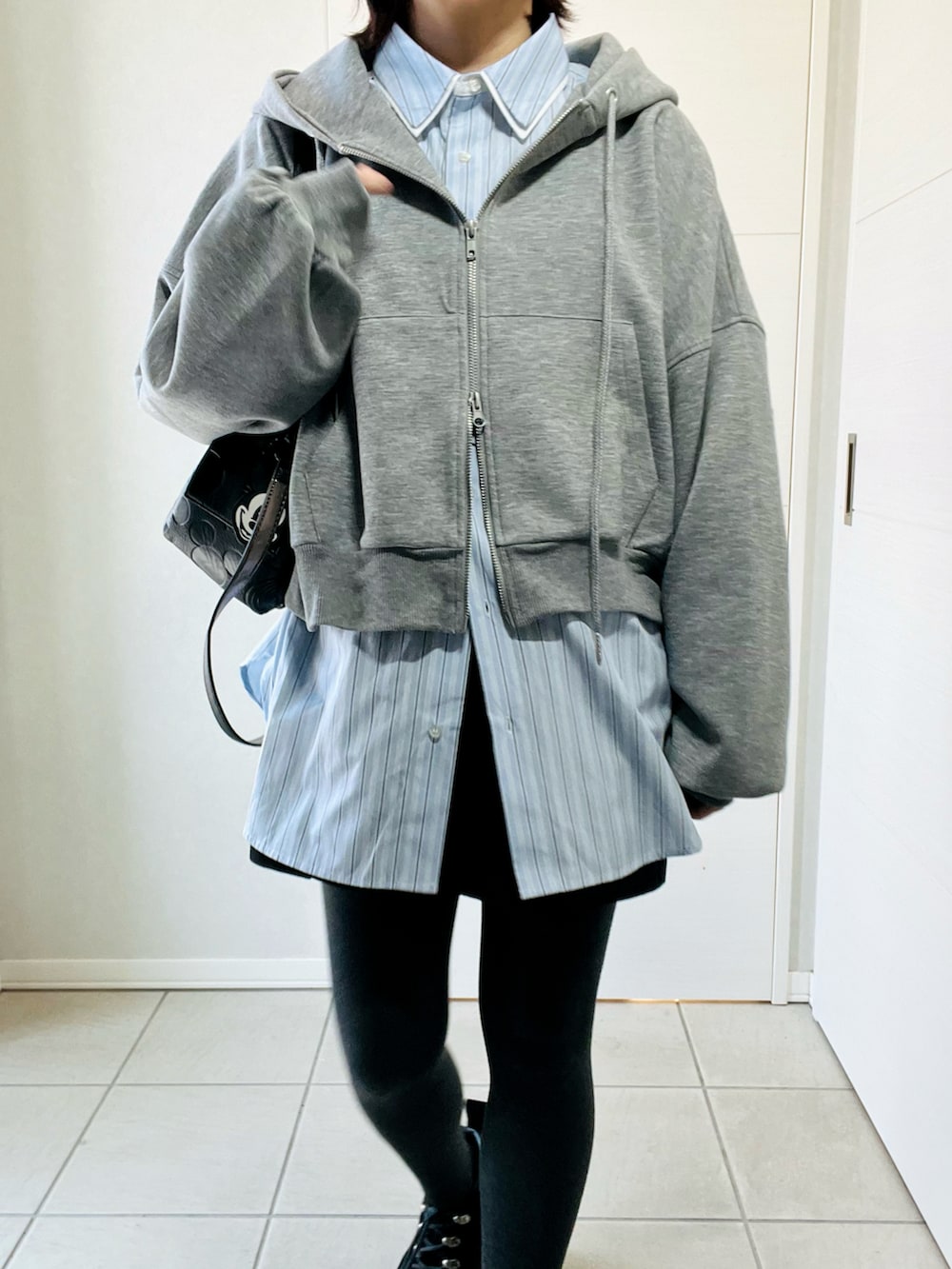 グレー系のパーカー、ブルー系のシャツ/ブラウス、ブラック系のその他パンツを着用したレディースの春コーディネートの2枚目の写真