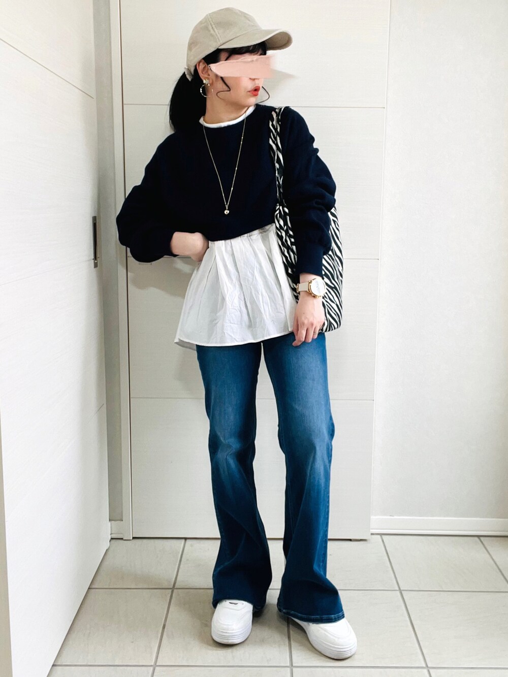 ブルー系のニット/セーター、ブルー系のデニムパンツ、ホワイト系のスニーカーを着用したレディースの春コーディネートの3枚目の写真