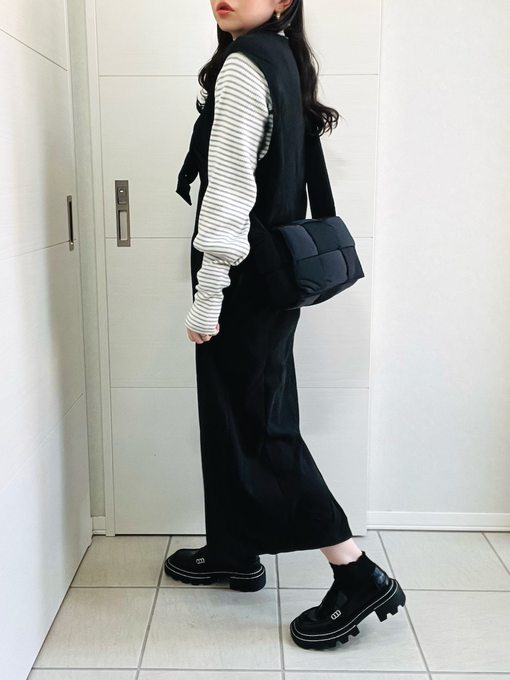 ブラック系のジャンパースカート、グレー系のニット/セーター、ブラック系のローファーを着用したレディースの秋コーディネートの4枚目の写真