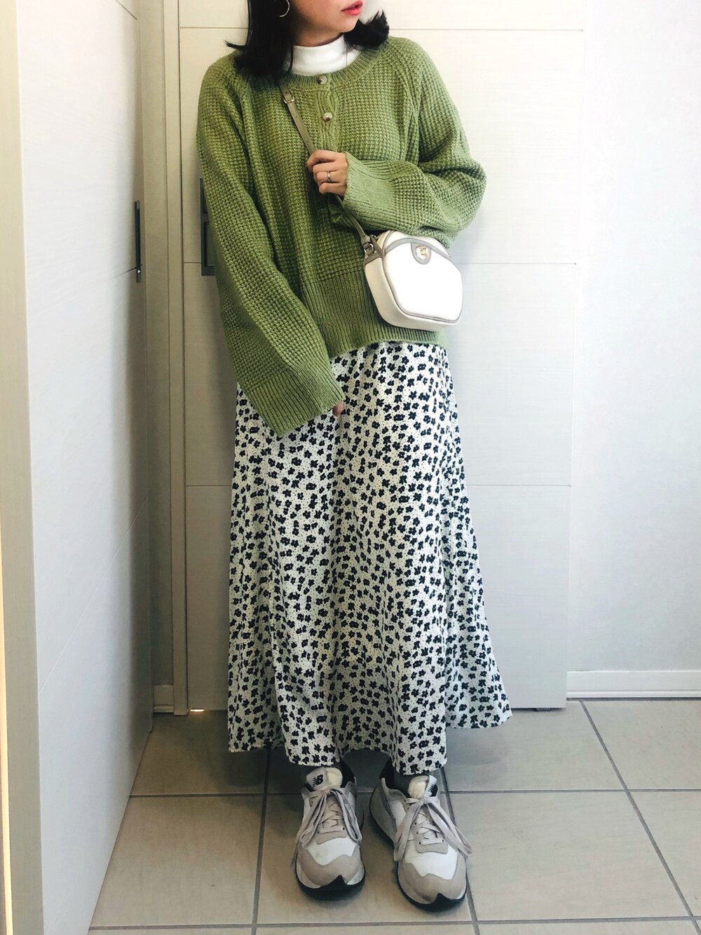 グリーン系のニット/セーター、ホワイト系のスカート、ホワイト系のスニーカーを着用したレディースの冬コーディネートの3枚目の写真