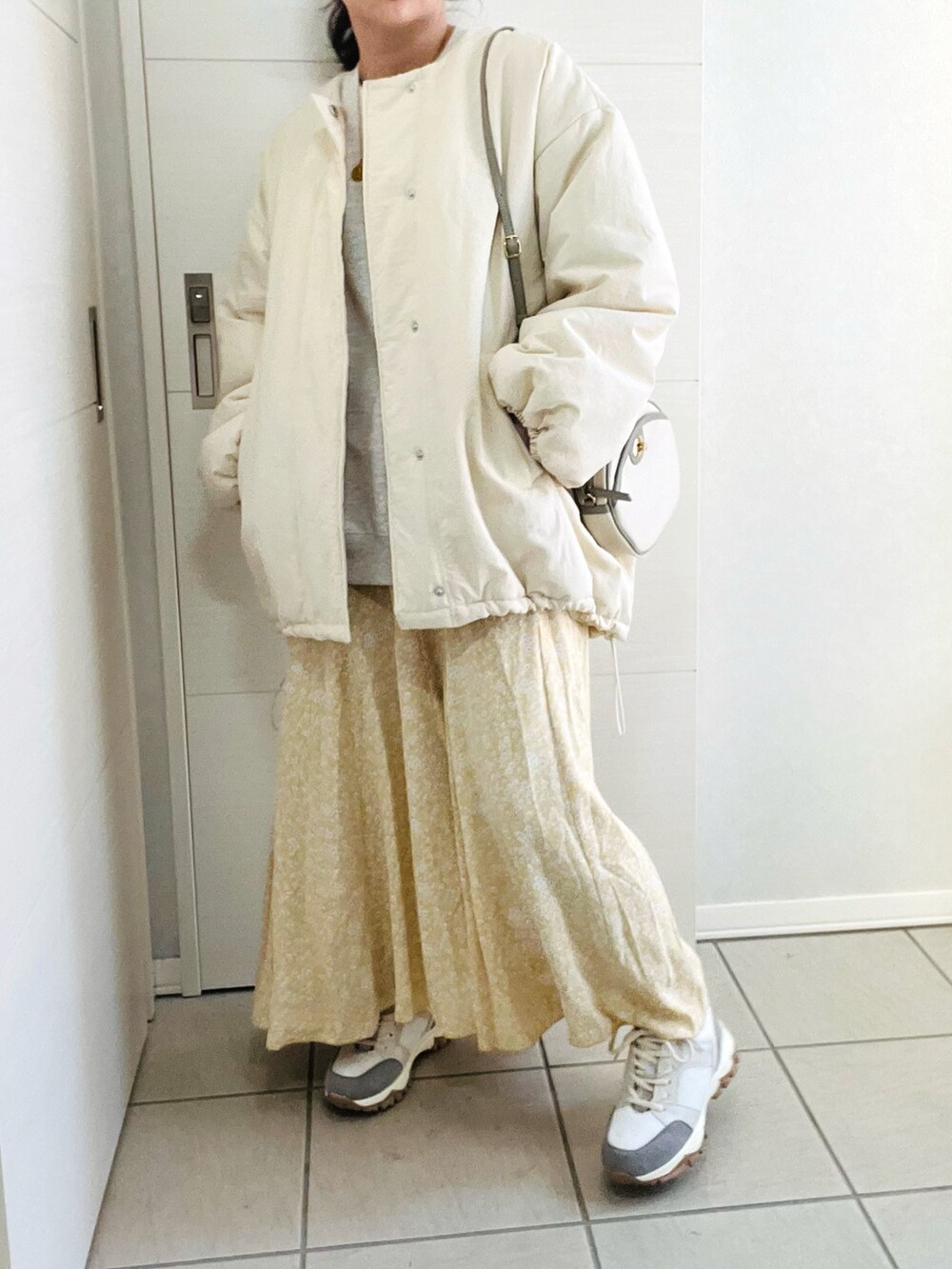 ホワイト系のブルゾン、グレー系のスウェット、イエロー系のスカートを着用したレディースの冬コーディネートの4枚目の写真