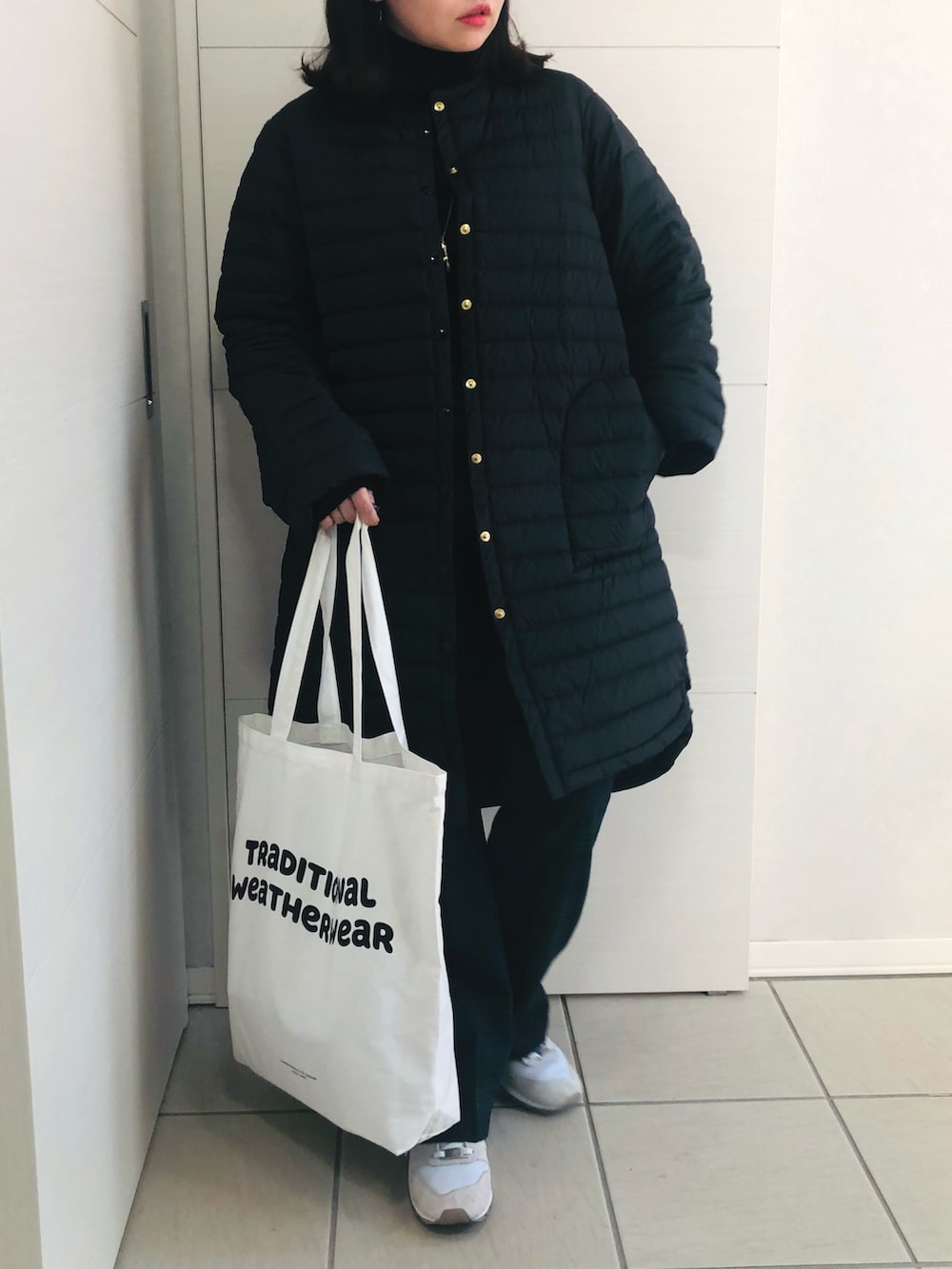 ブラック系のダウンジャケット/コート、ブラック系のニット/セーター、グリーン系のスラックスを着用したレディースの冬コーディネートの2枚目の写真